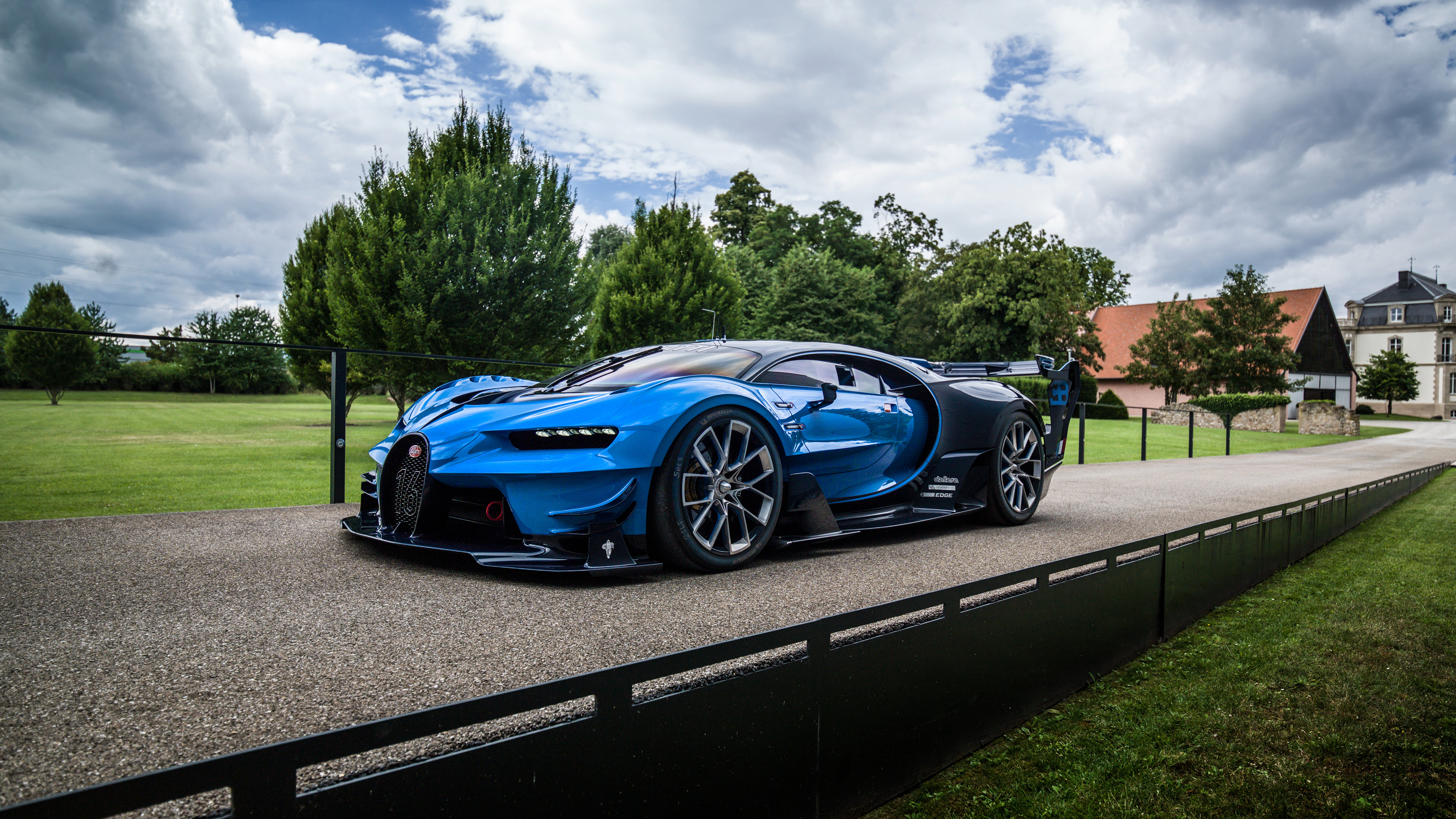 A sleek, futuristic Bugatti concept car, the Bugatti Vision Gran Turismo, parked on a paved driveway leading to a French chateau