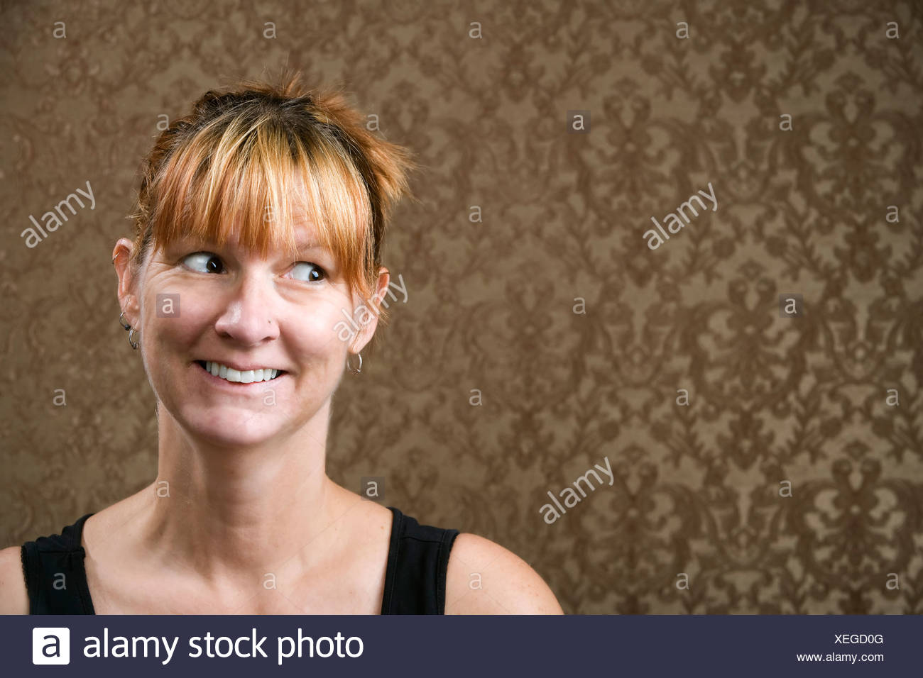 Pretty Woman Smiling In Front Of A Gold Flocked Wallpaper