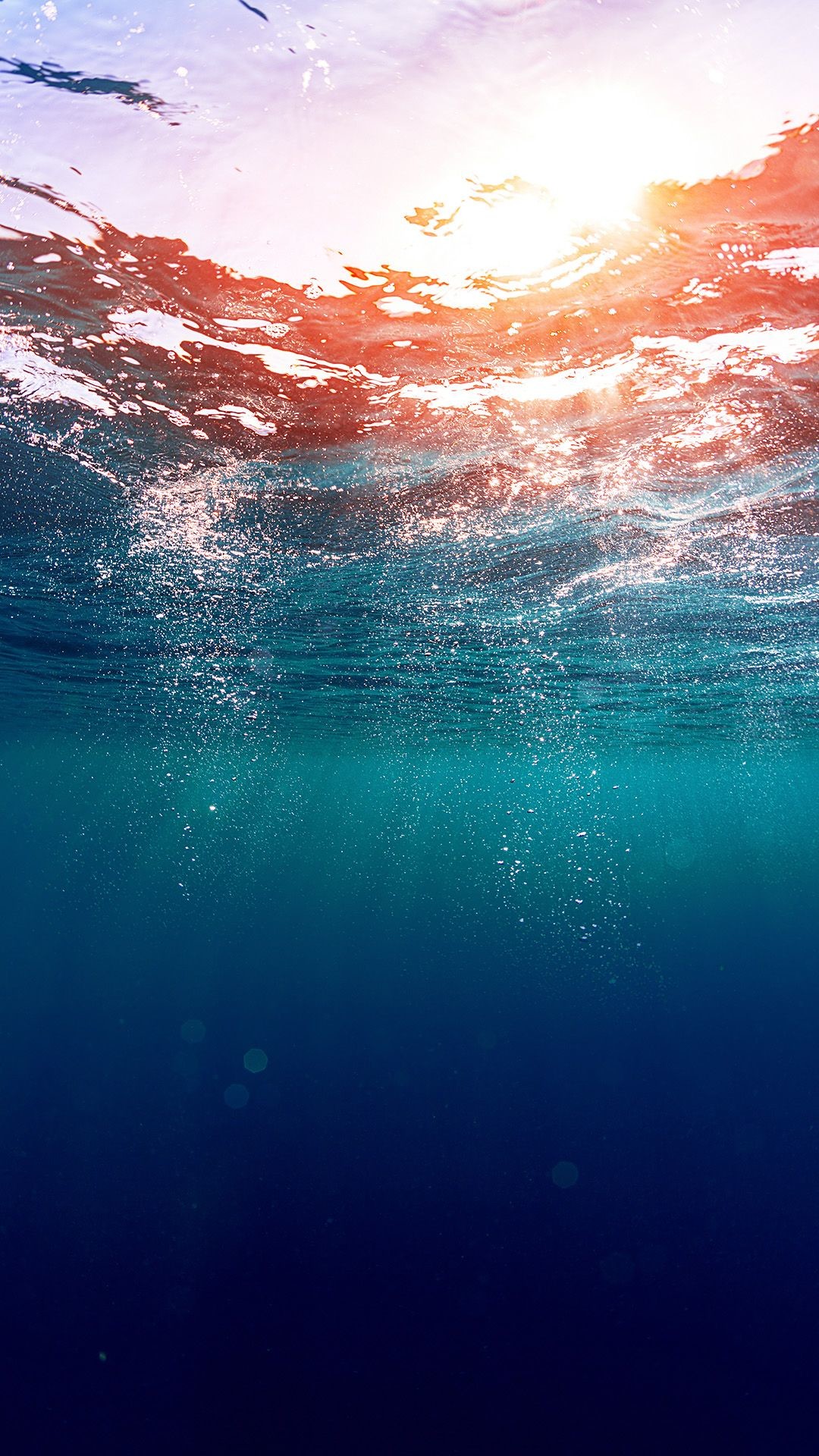 Underwater view of the ocean with sunlight shimmering through the surface
