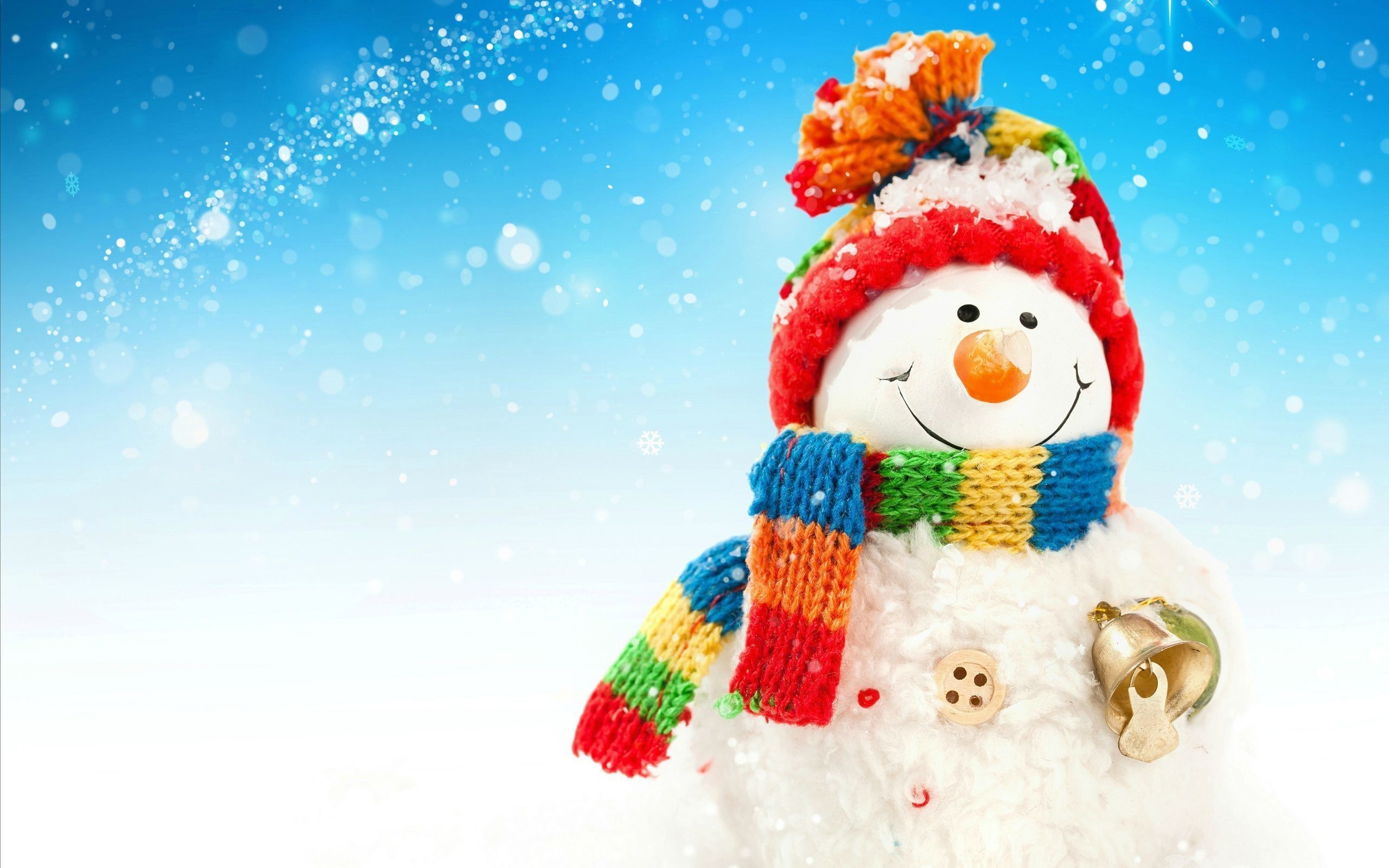 A cheerful snowman figurine stands against a snowy blue backdrop, wearing a colorful knit hat and scarf and holding a golden bell. Perfect for winter holiday themes