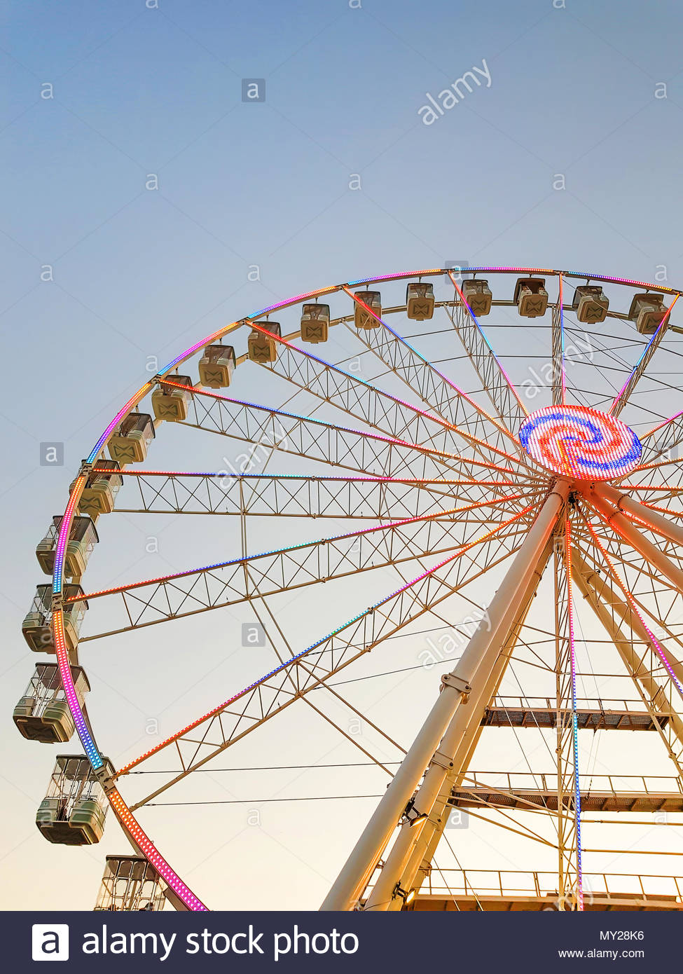 Part of ferris wheel against a blue sky background with colorful