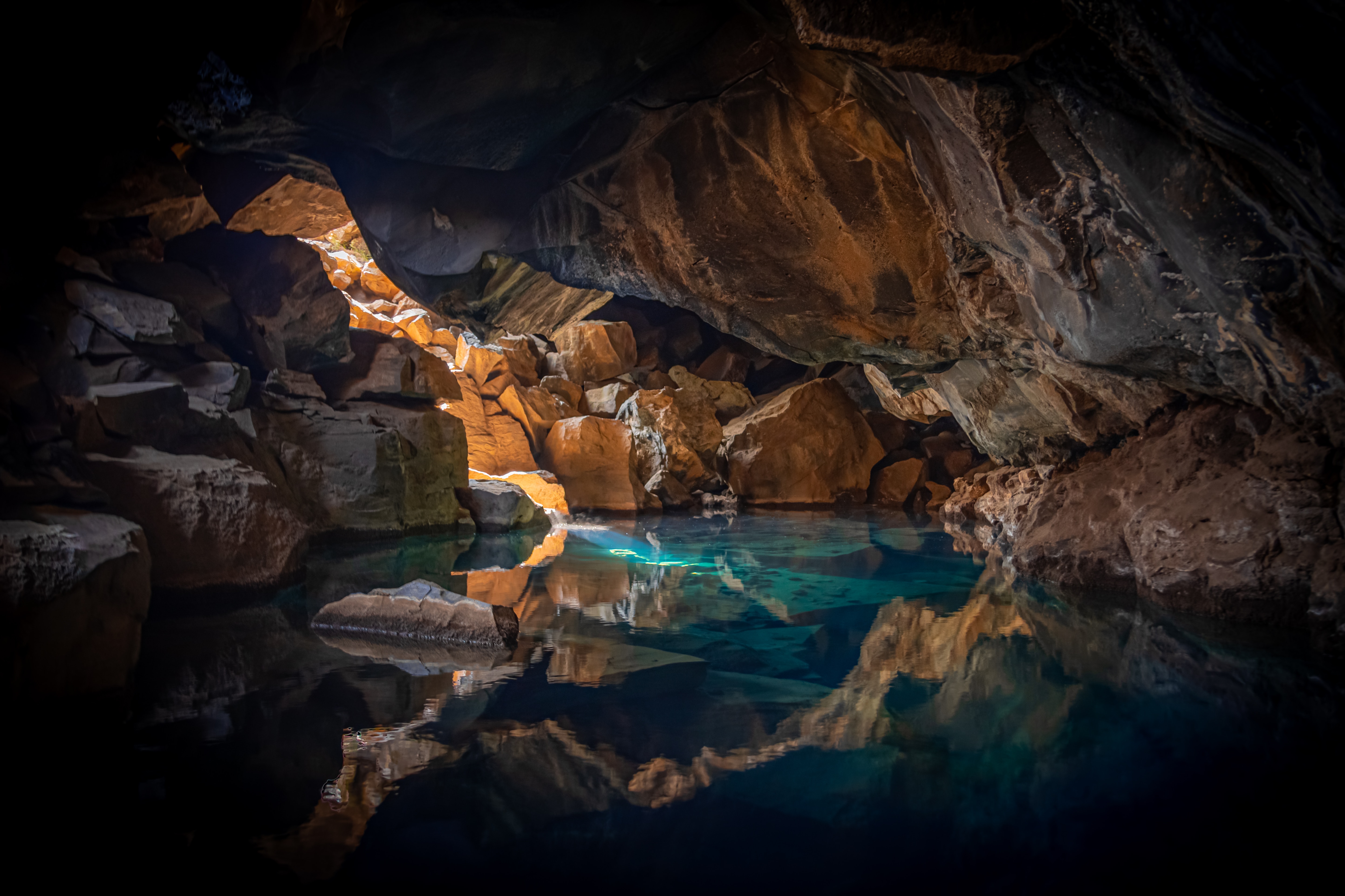 A mesmerizing view inside a cave with a crystal-clear underground lake reflecting the rock formations above