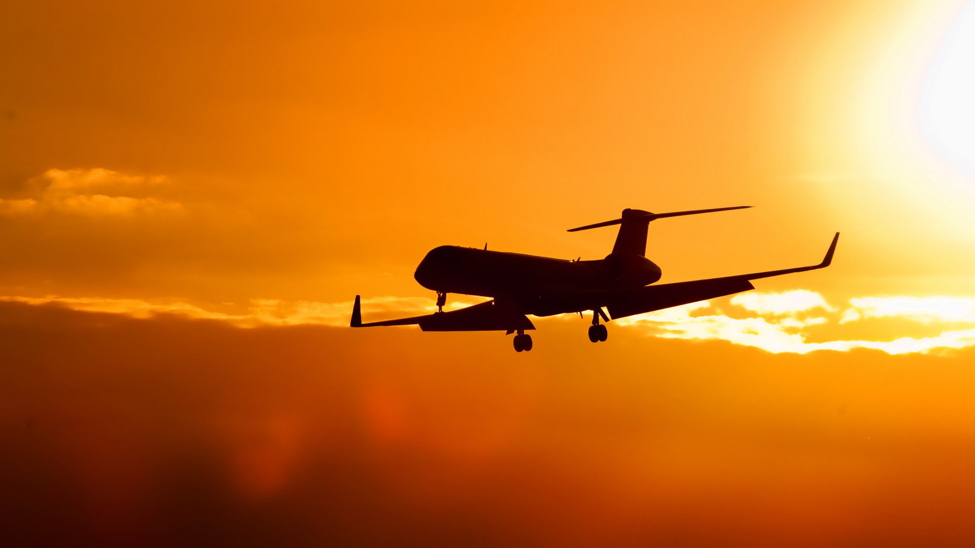 Silhouette of a private jet against a vibrant sunset sky