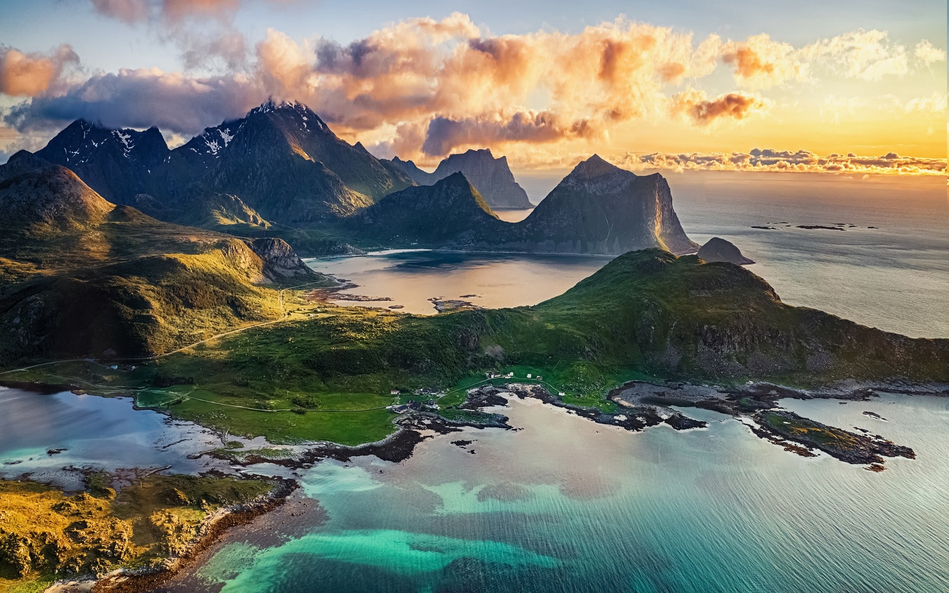 Aerial view of a stunning island landscape at sunset, featuring turquoise waters, rugged mountains, and lush green vegetation