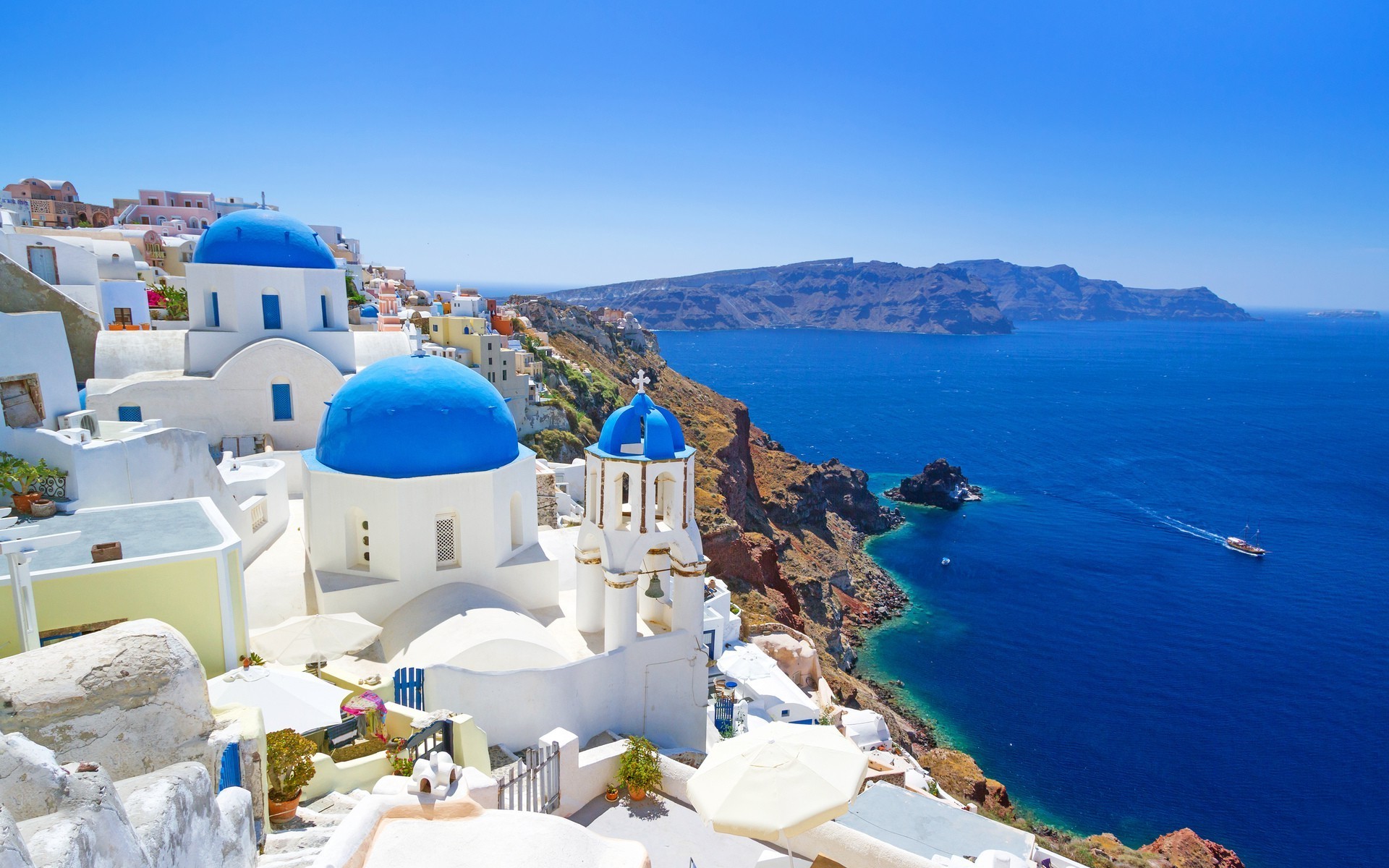 Santorini, Greece: A picturesque view of white-washed buildings with blue domes overlooking the Aegean Sea