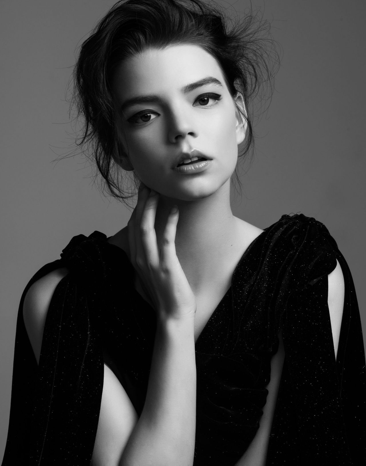 Anya Taylor-Joy strikes a pose in a black velvet dress. This black and white portrait captures her unique beauty and style