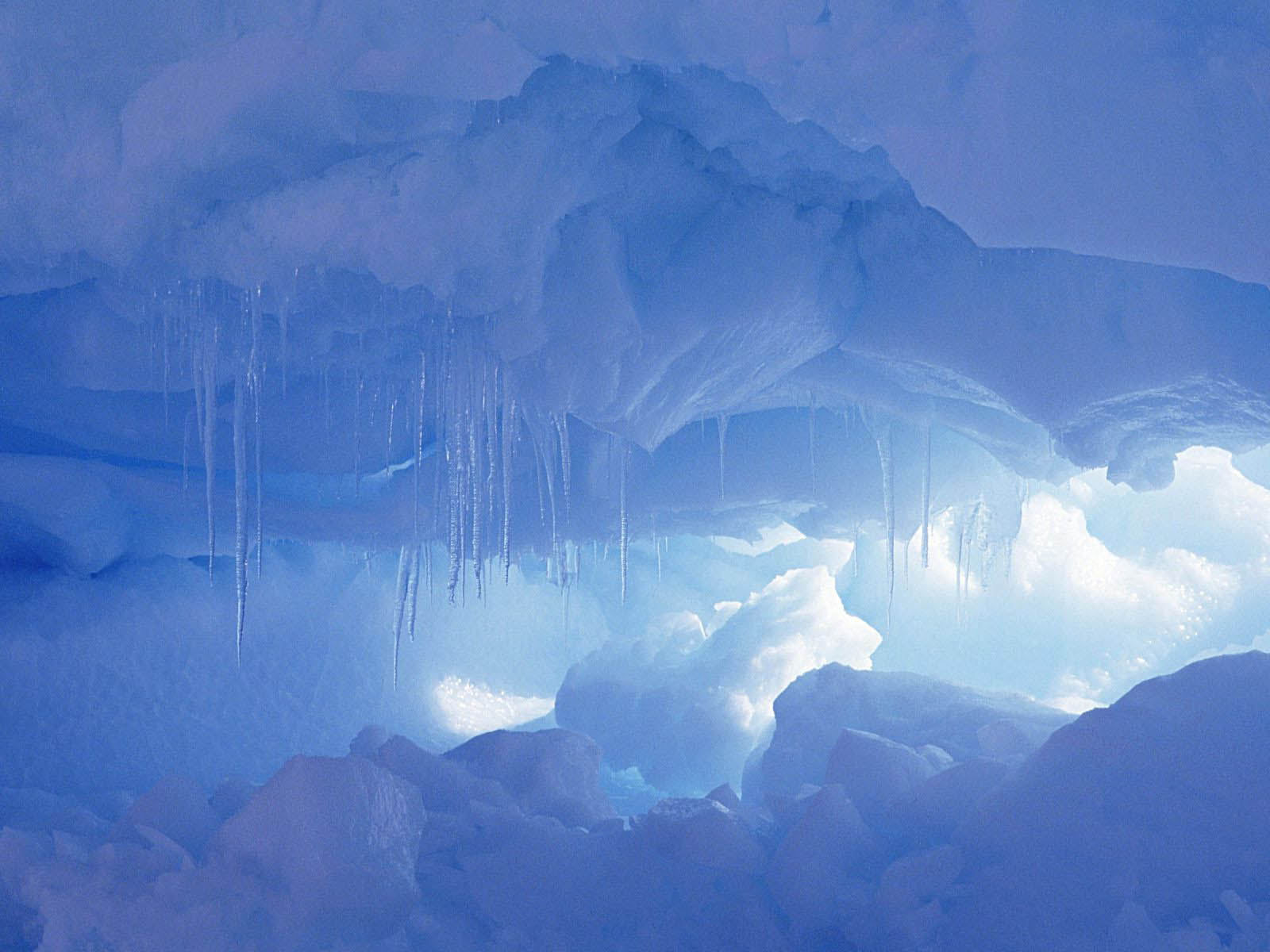 Icicles hanging from the ceiling of an ice cave, glowing with a soft blue light