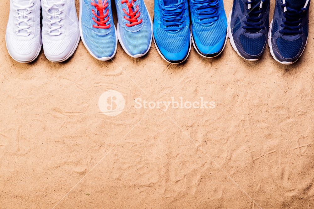 Various Sports Shoes In A Row Against Sand Background Studio Shot