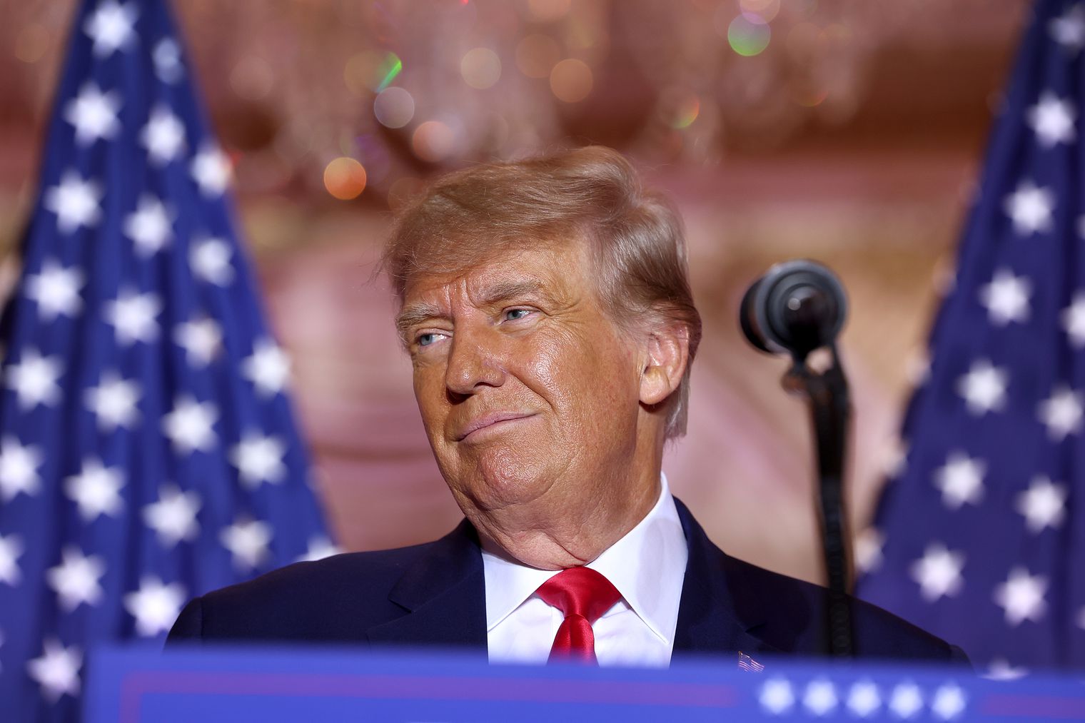 Donald Trump at a 2024 campaign event, standing before American flags