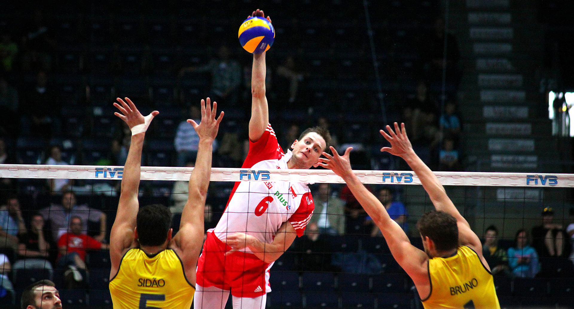A volleyball player spiking the ball over the net during a professional match