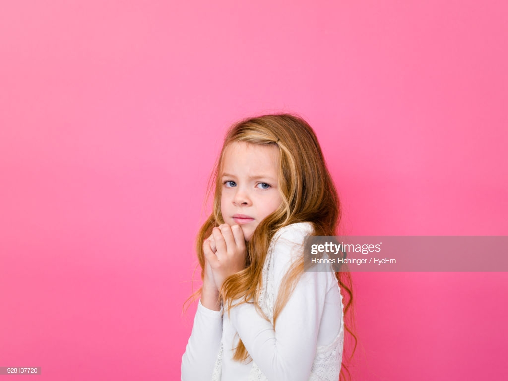 Portrait Of Worried Girl Against Pink Background Stock Photo