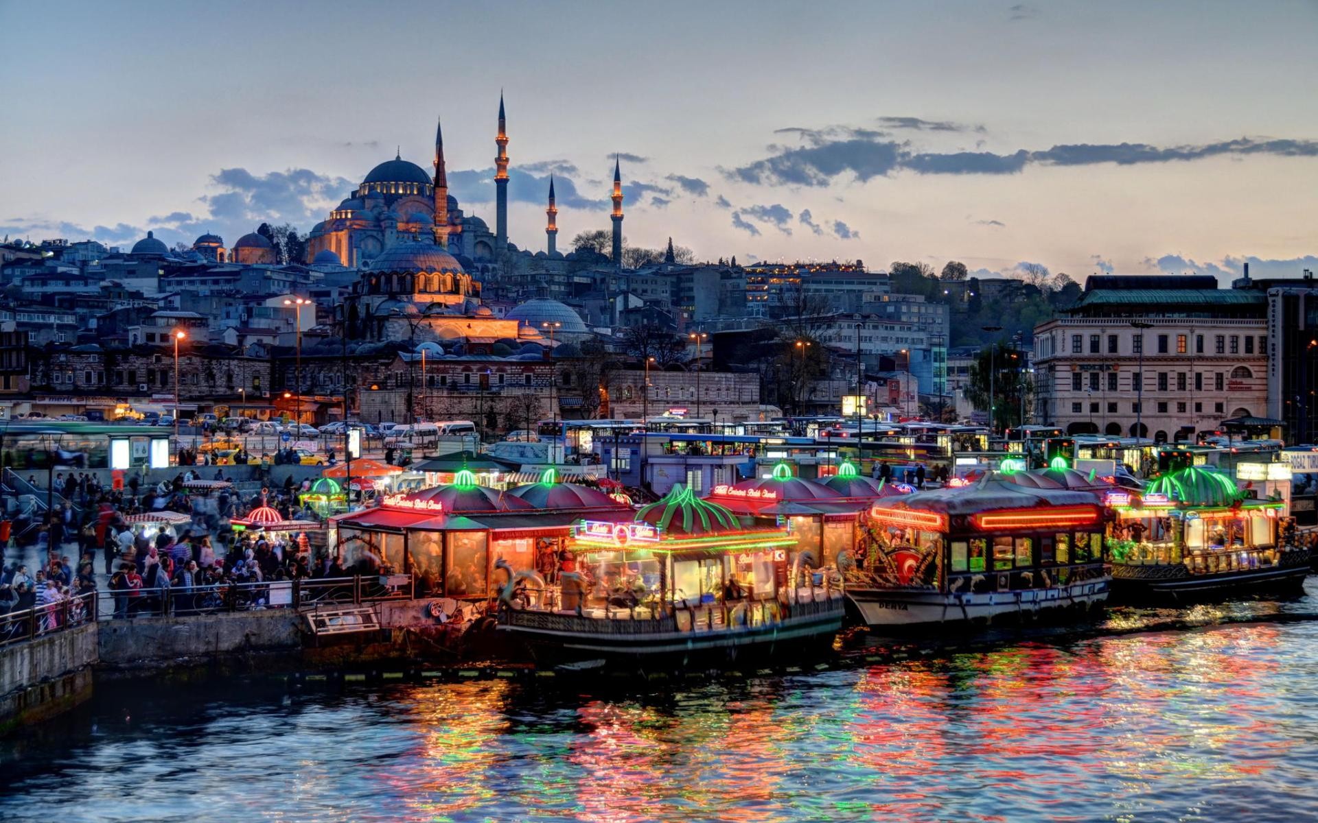 Evening view of the Suleymaniye Mosque from the Golden Horn in Istanbul, Turkey, with illuminated floating restaurants in the foreground