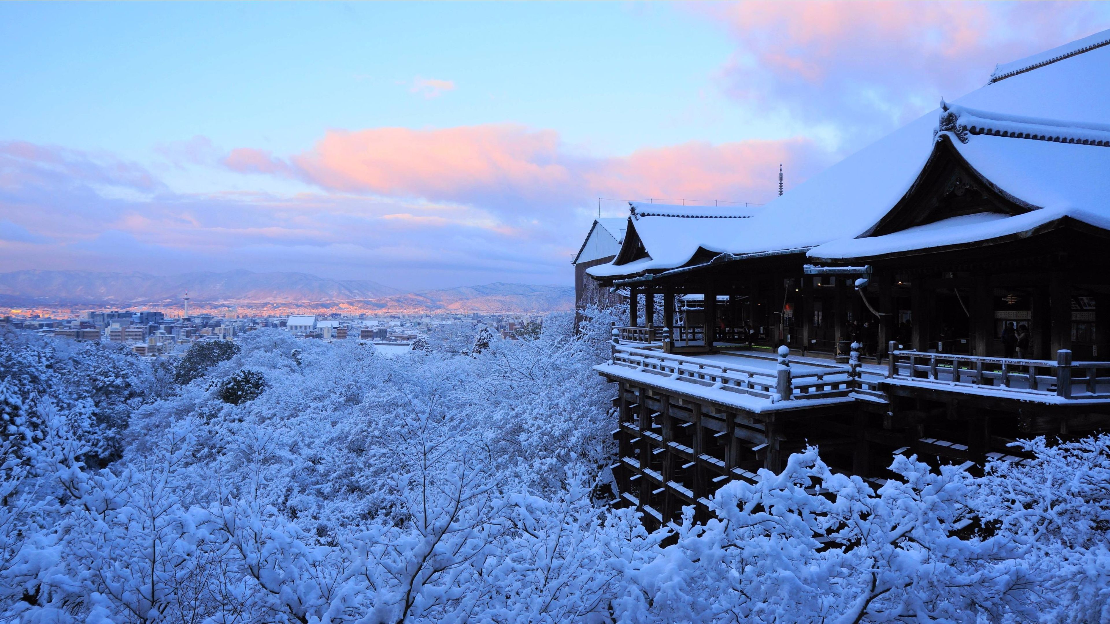 A breathtaking 4k wallpaper of a snow-covered Japanese temple overlooking a city at dawn