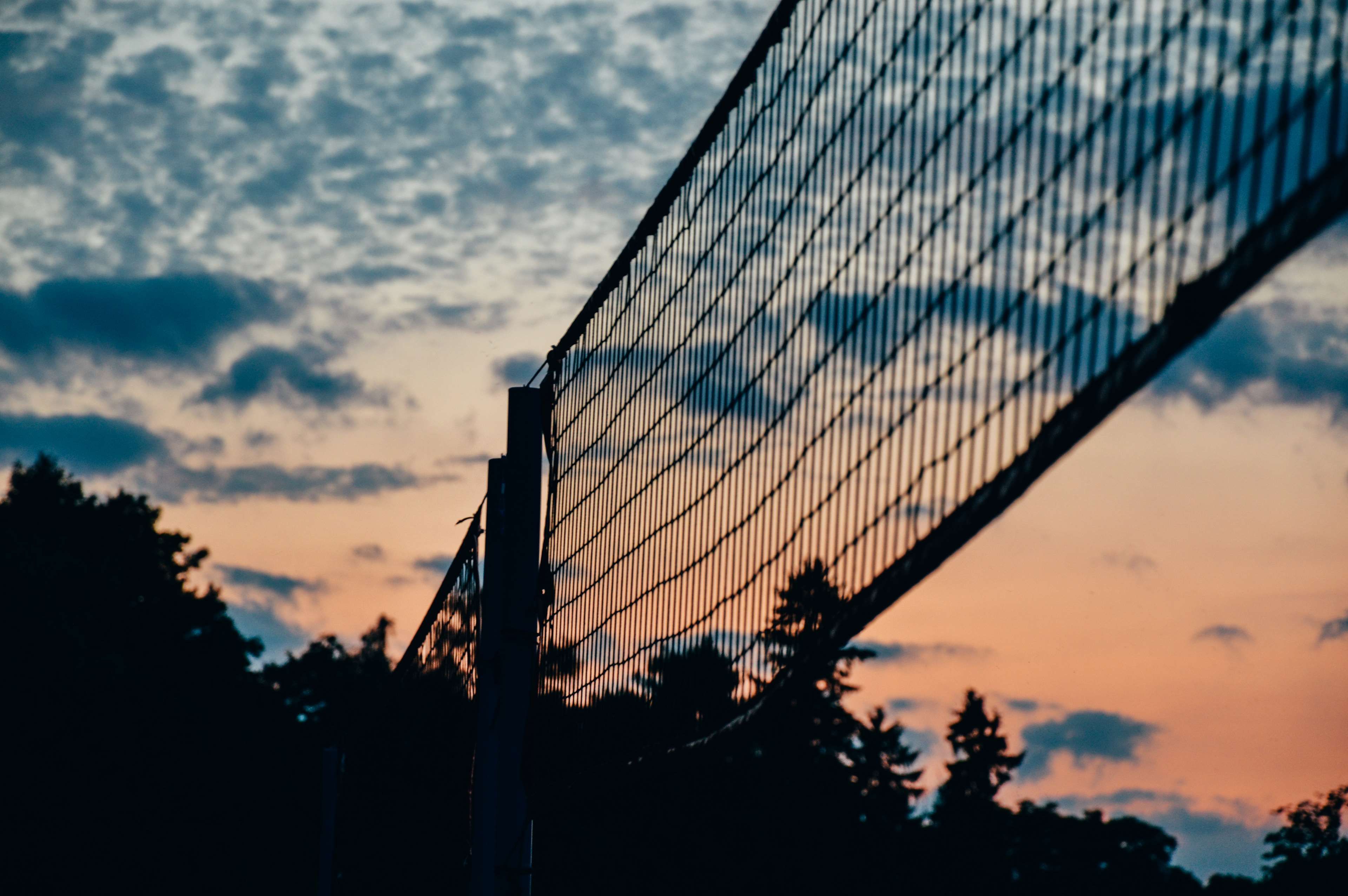 Silhouette of a volleyball net against a vibrant sunset sky