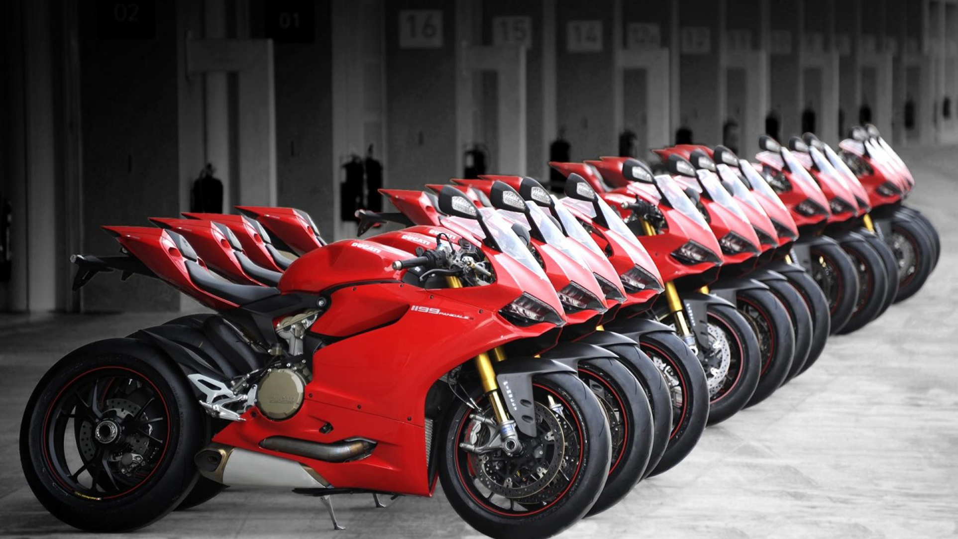 A row of red Ducati 1199 Panigale motorcycles parked in a garage