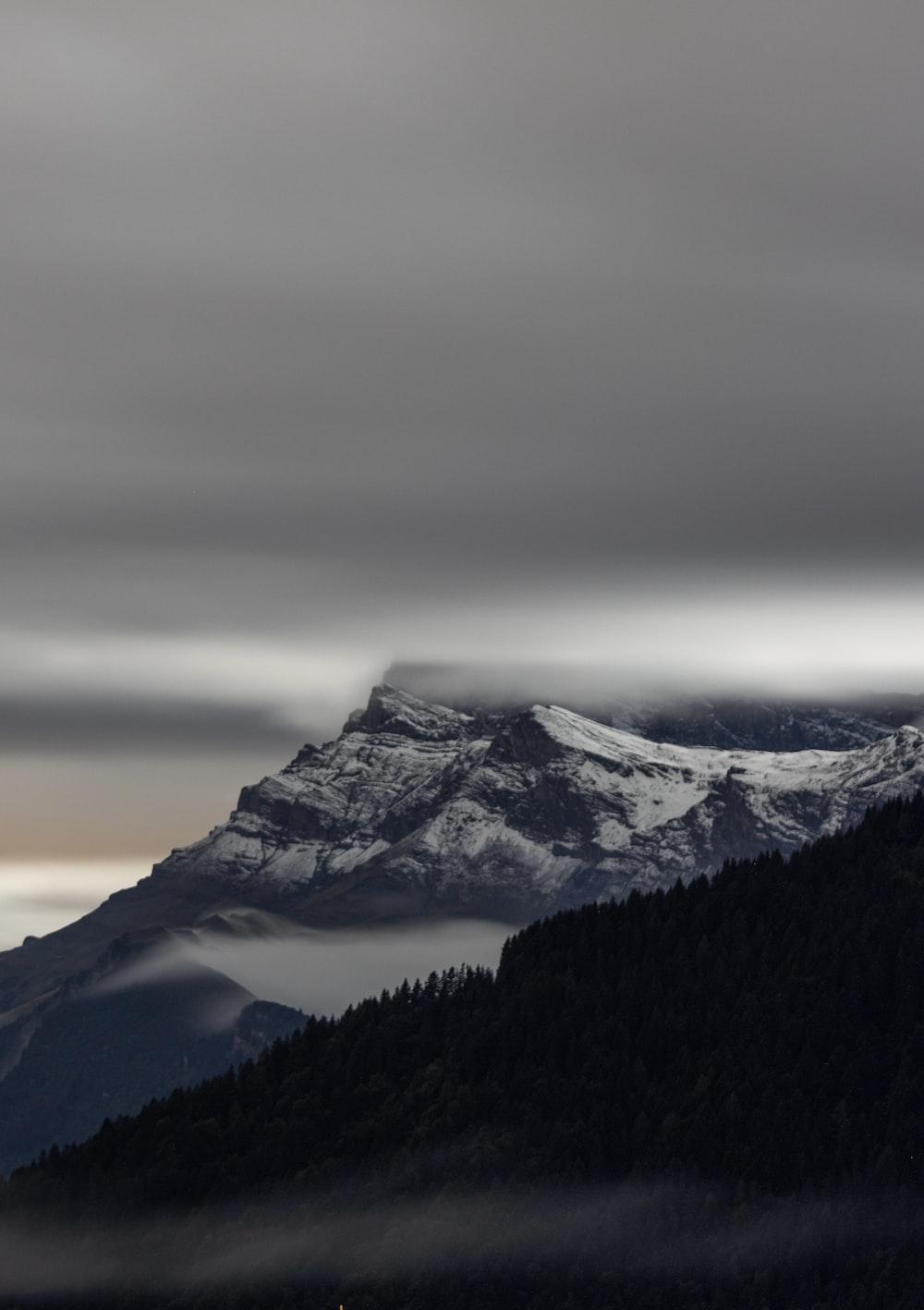 A Mountain Covered In Snow And Clouds Under Cloudy Sky Photo