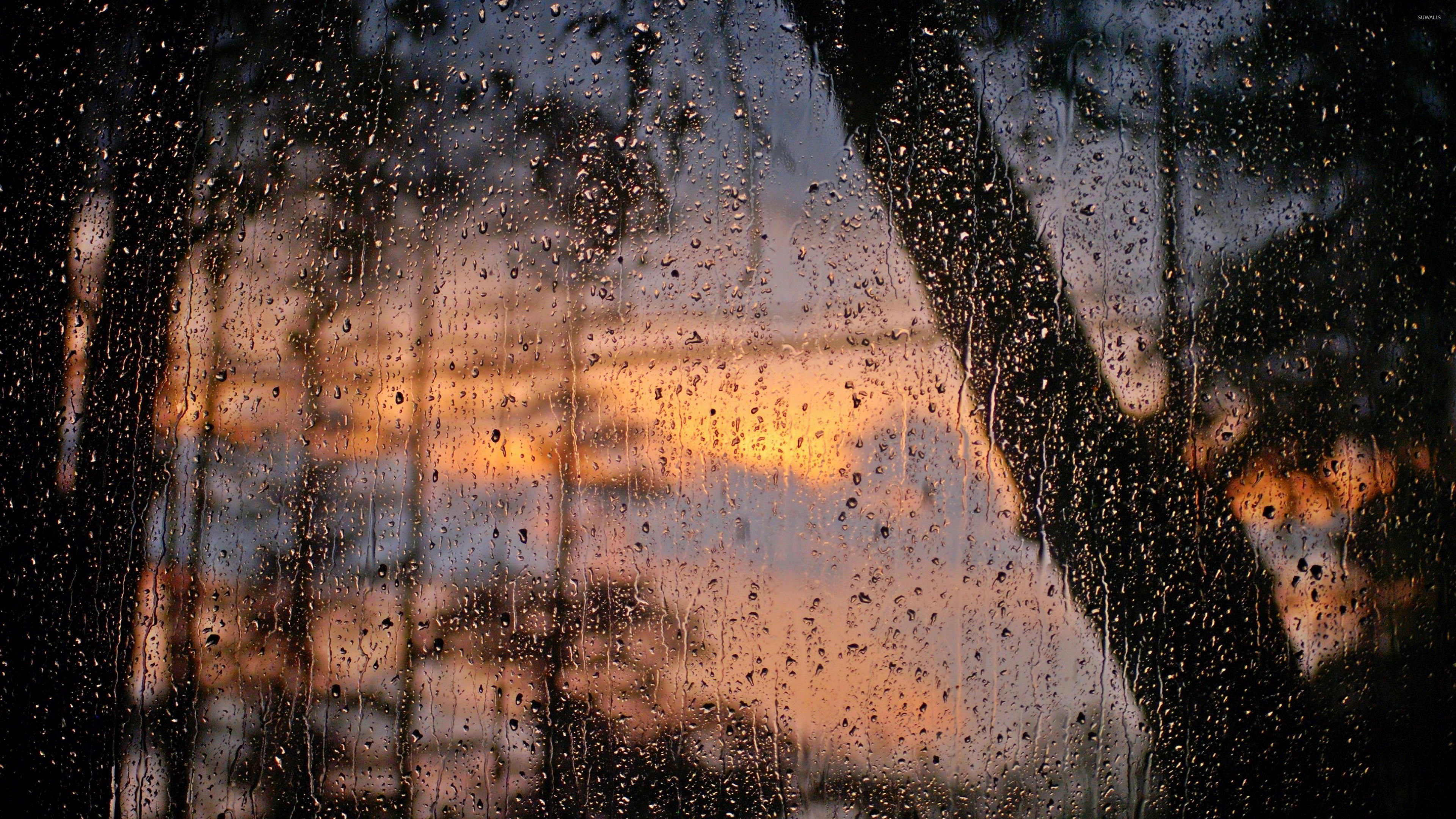 Raindrops on a window pane during a vibrant sunset, creating a beautiful and abstract pattern