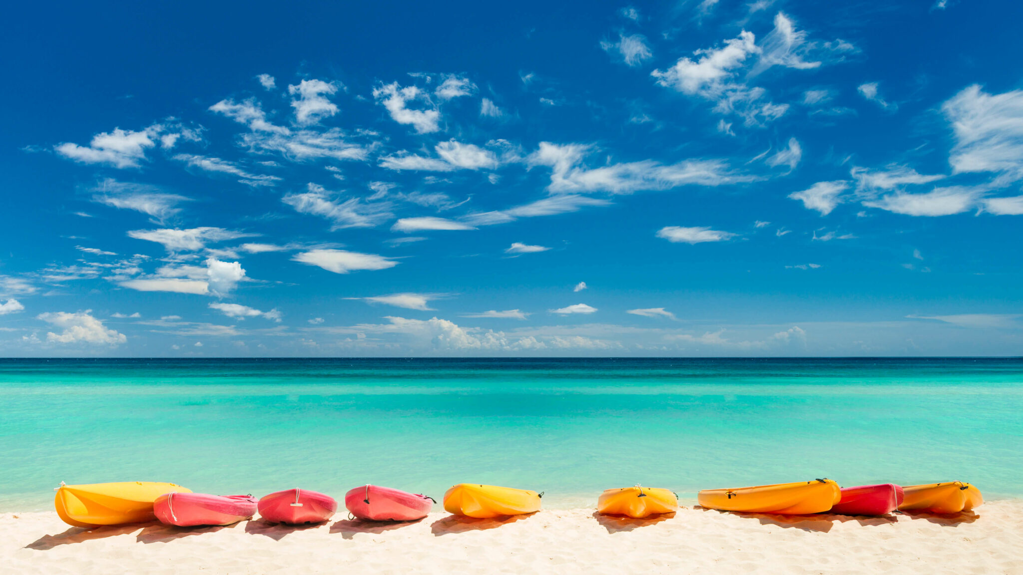 Vibrant kayaks on a tropical beach with turquoise water and blue sky