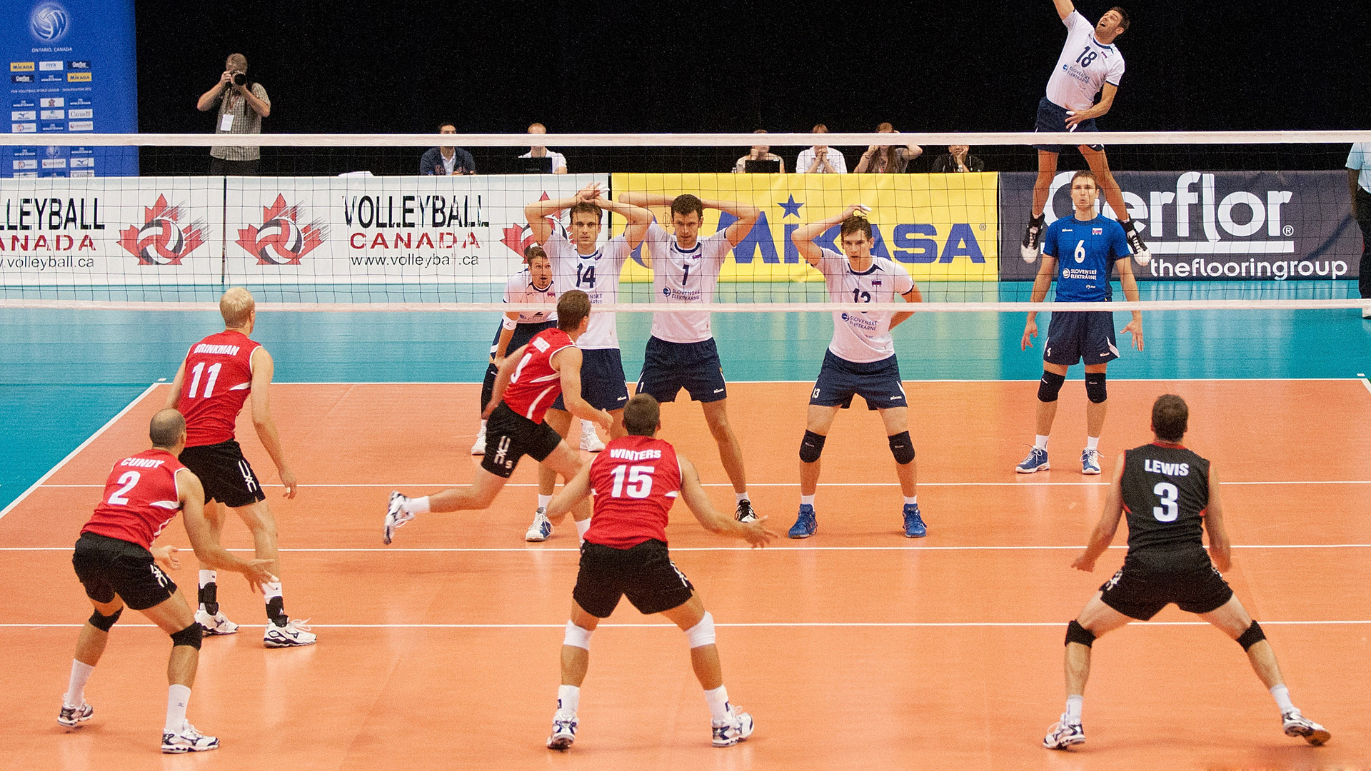 Professional volleyball players in action during a dynamic match, showcasing athleticism and teamwork on the court
