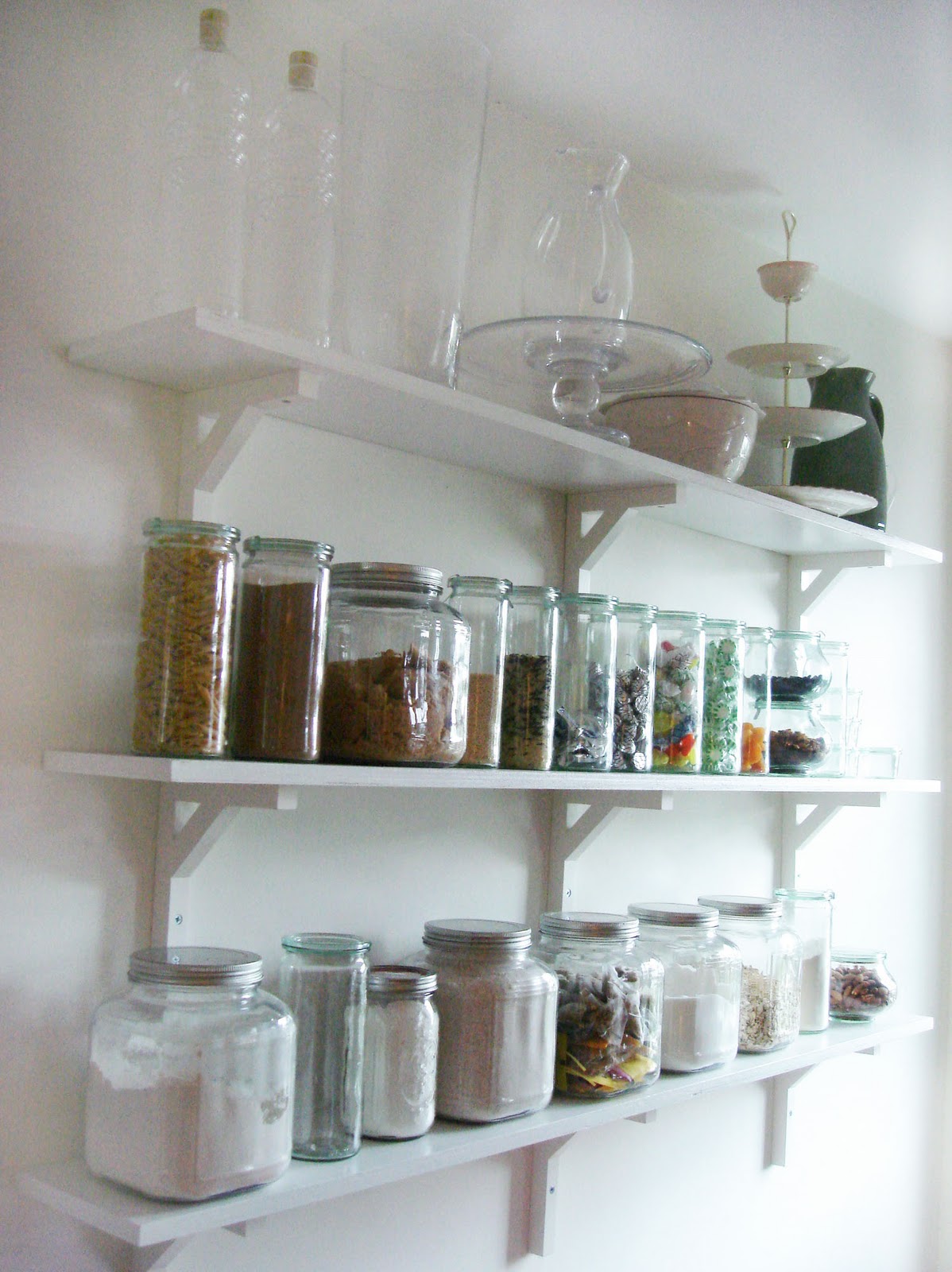 Kitchen Pantry With White Pitchers On Shelves And Bottles Jars