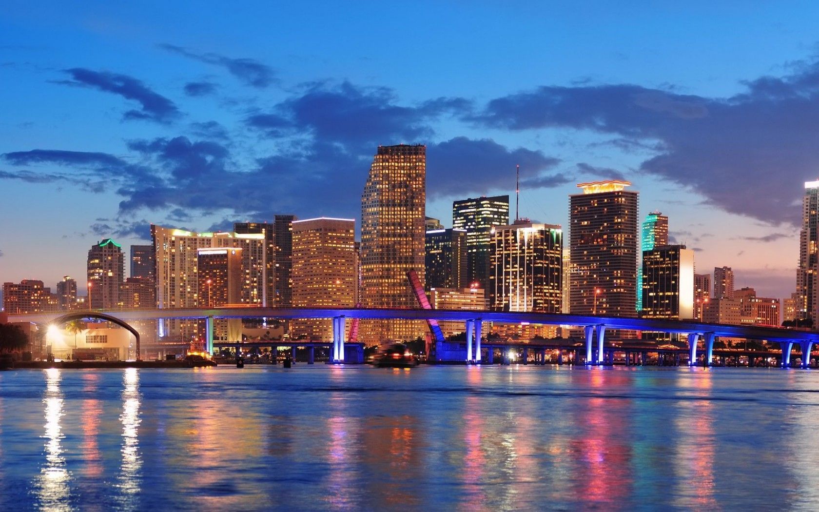 Stunning night view of the Miami skyline with illuminated buildings and a bridge reflecting in the water