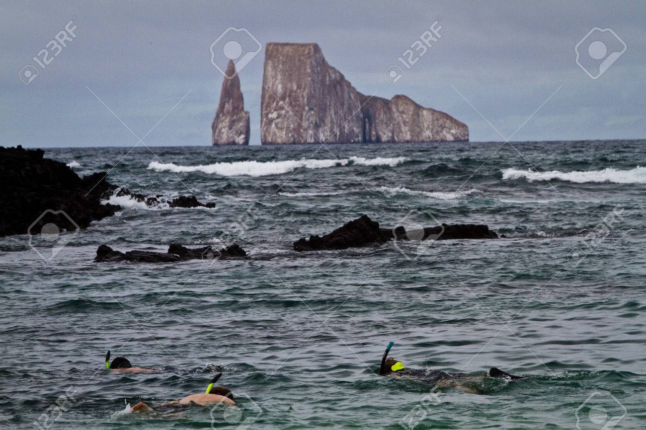 Tourists Snorkeling With Kicker Rock Island In The Background