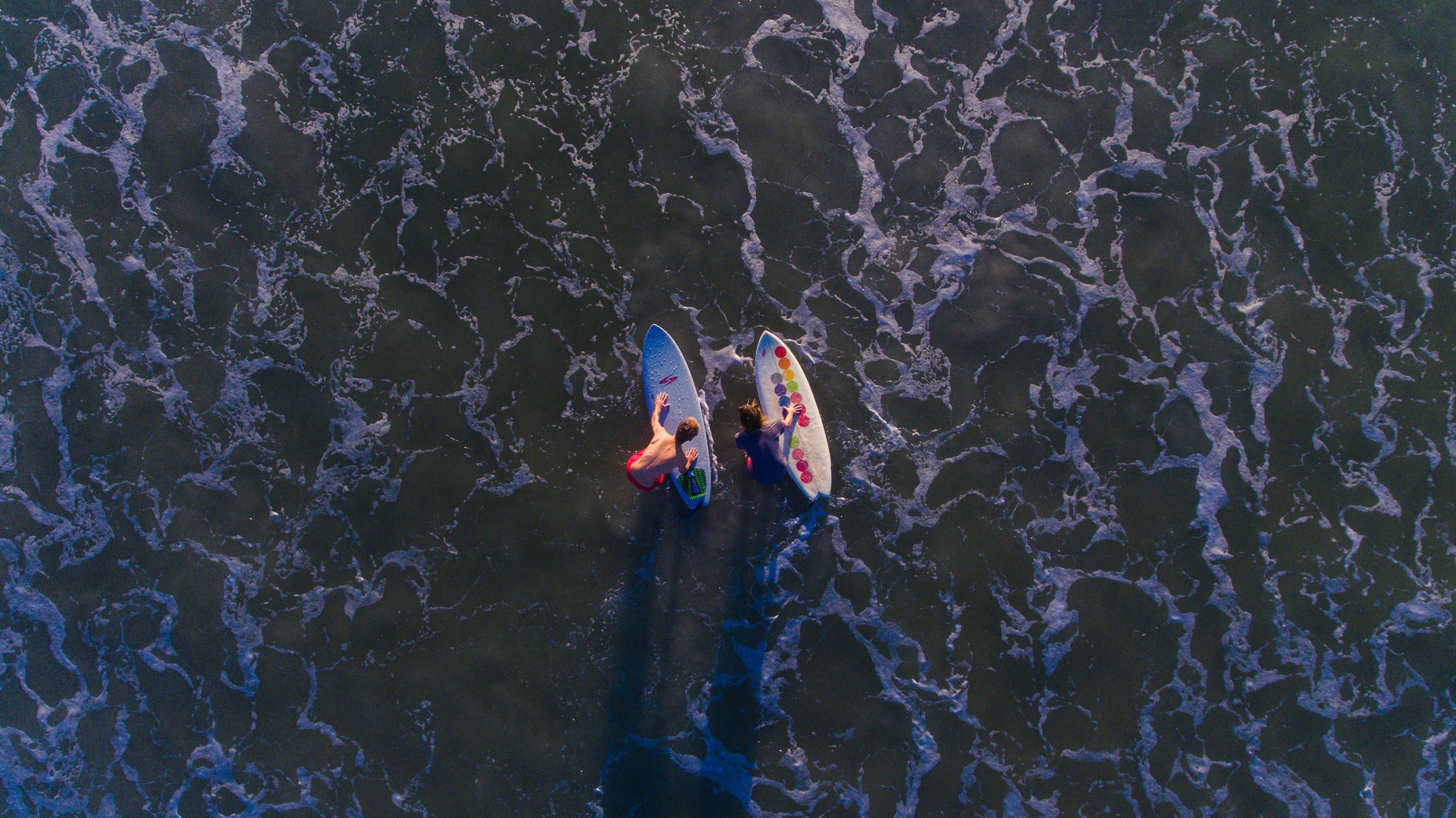 A Drone Shot Aerial Of Two Surfers On Their Boards At