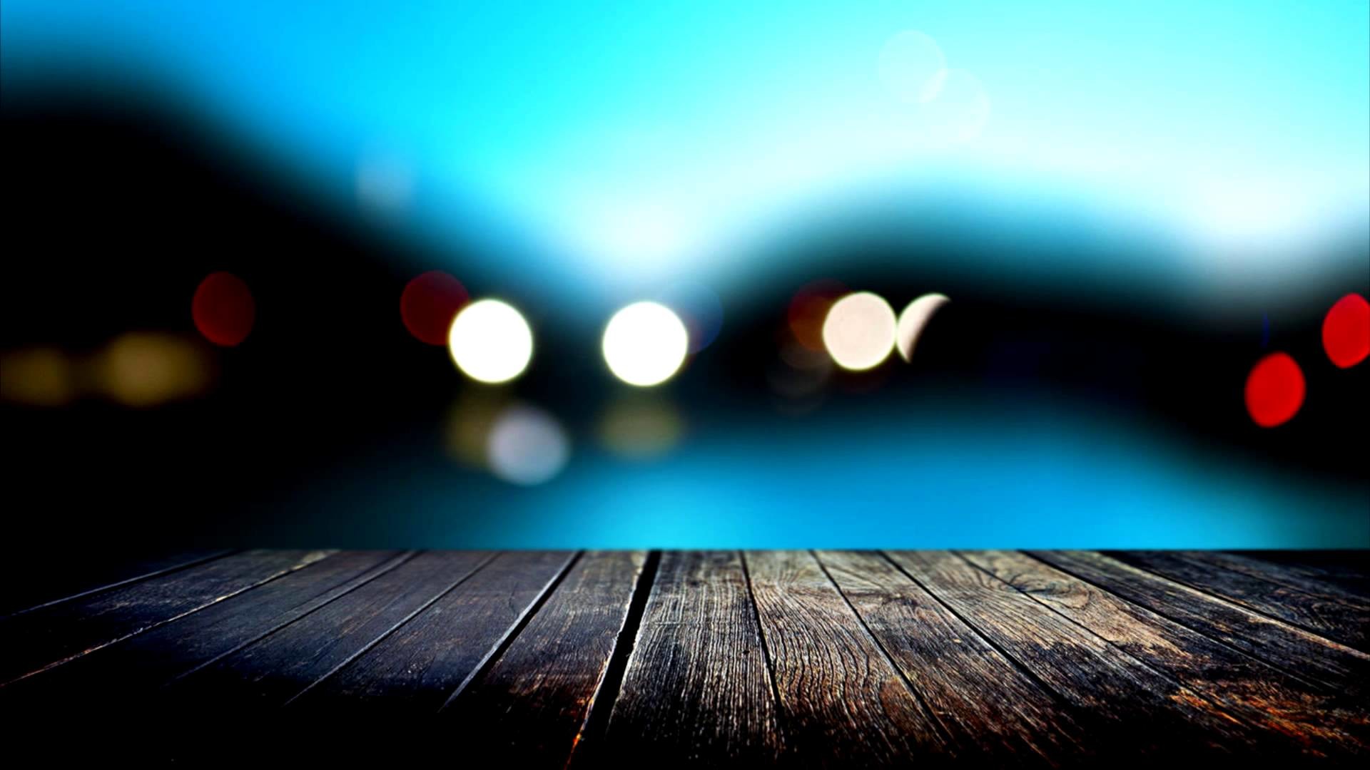Dark wooden planks against a defocused backdrop of city lights at night