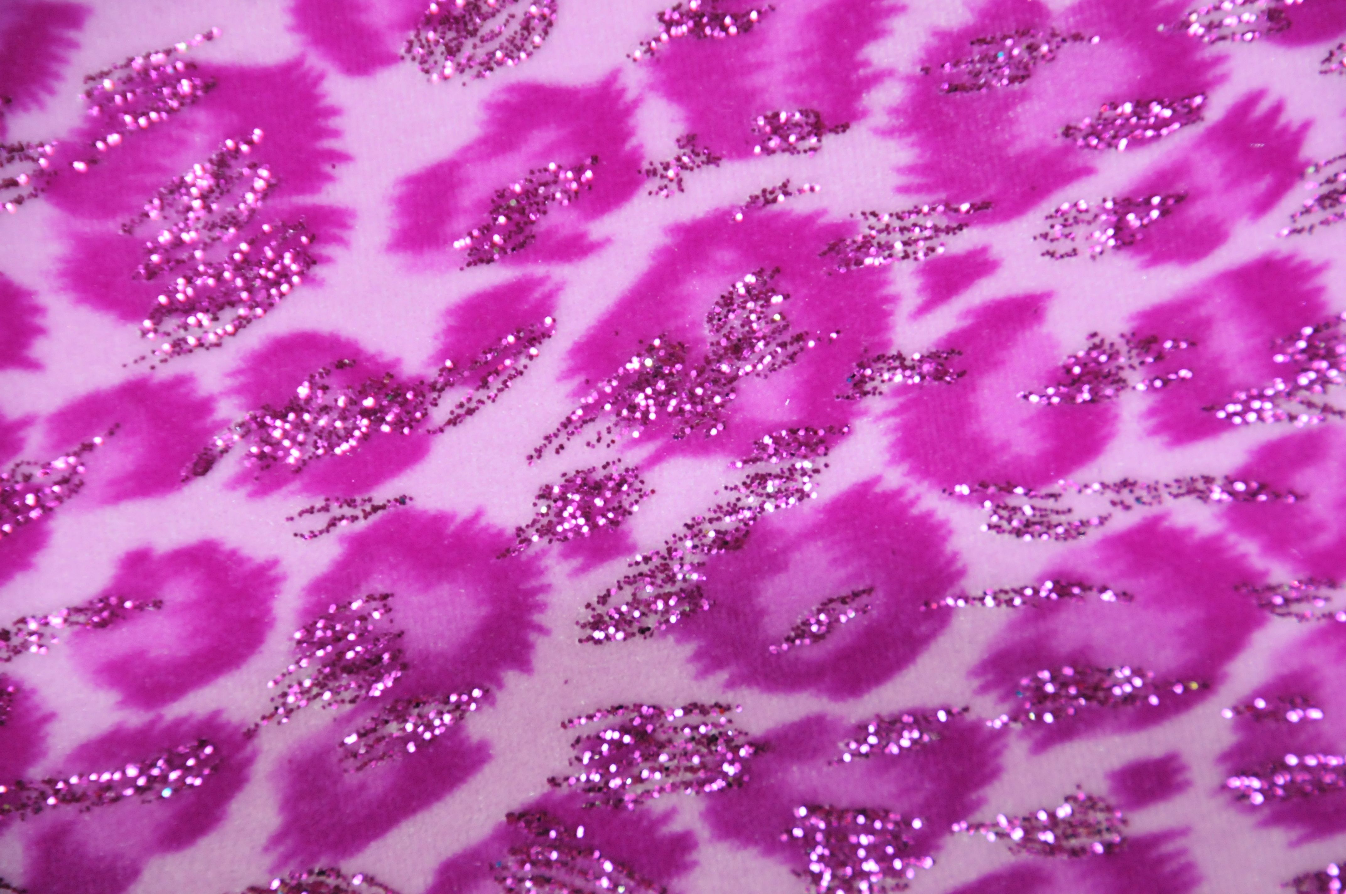 Close-up of a vibrant pink leopard print fabric adorned with sparkling glitter accents, adding a glamorous and textured touch