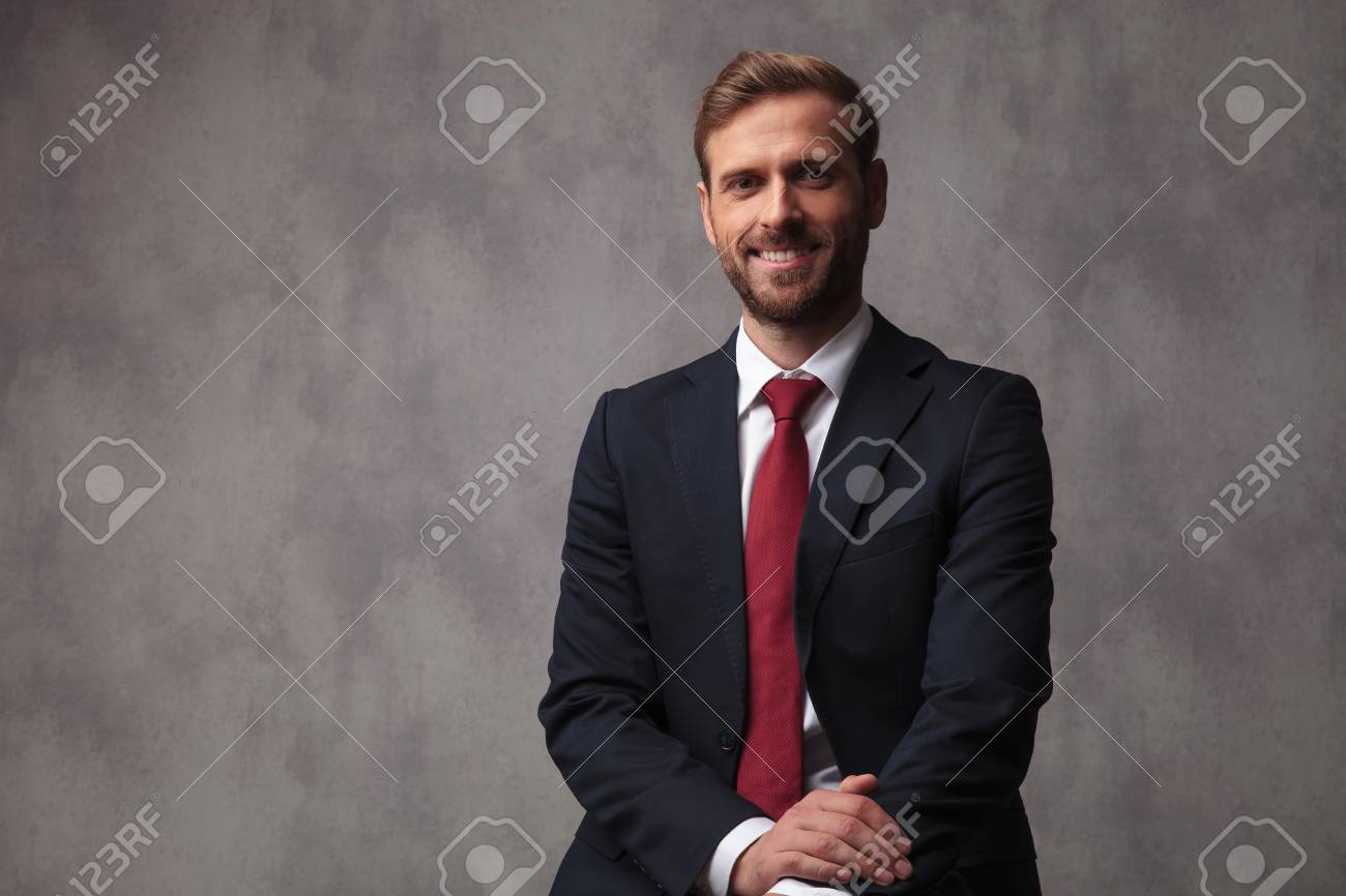 Young Businessman Smiling And Posing Against Grey Studio Wallpaper