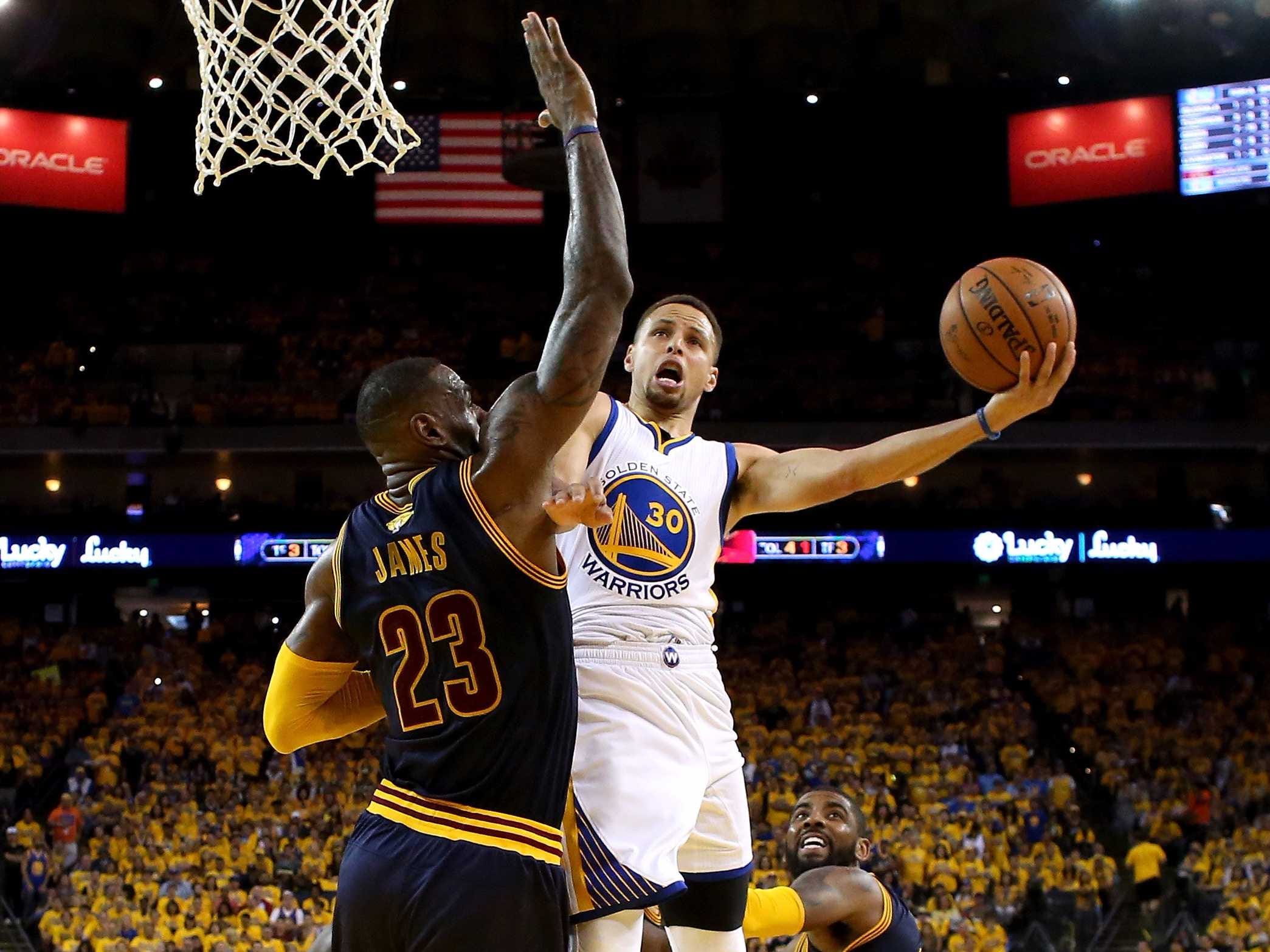LeBron James and Stephen Curry battling for a rebound in a Golden State Warriors vs. Cleveland Cavaliers game