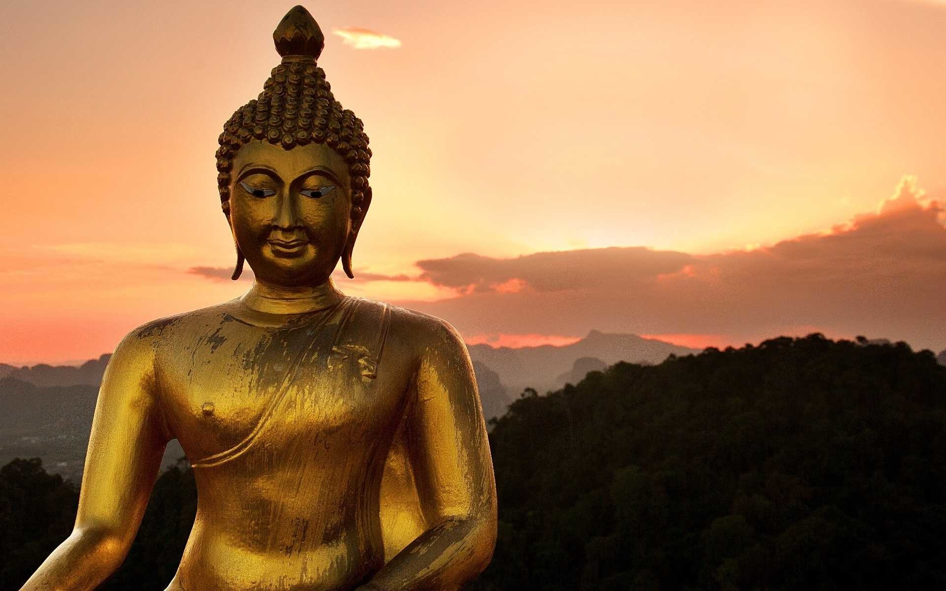 Serene golden Buddha statue against a sunset backdrop