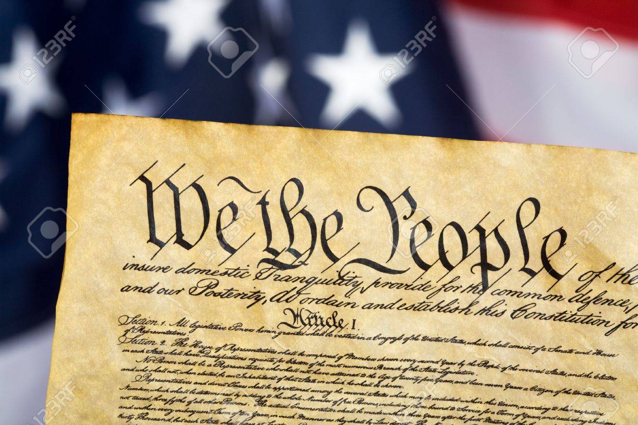 United States Constitution With Flag In Background Stock Photo