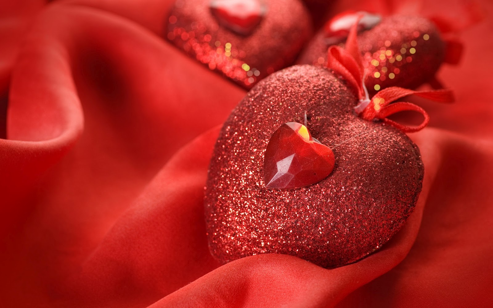 Close-up of sparkling red heart ornaments on a luxurious red satin background, perfect for Valentine's Day or romantic settings