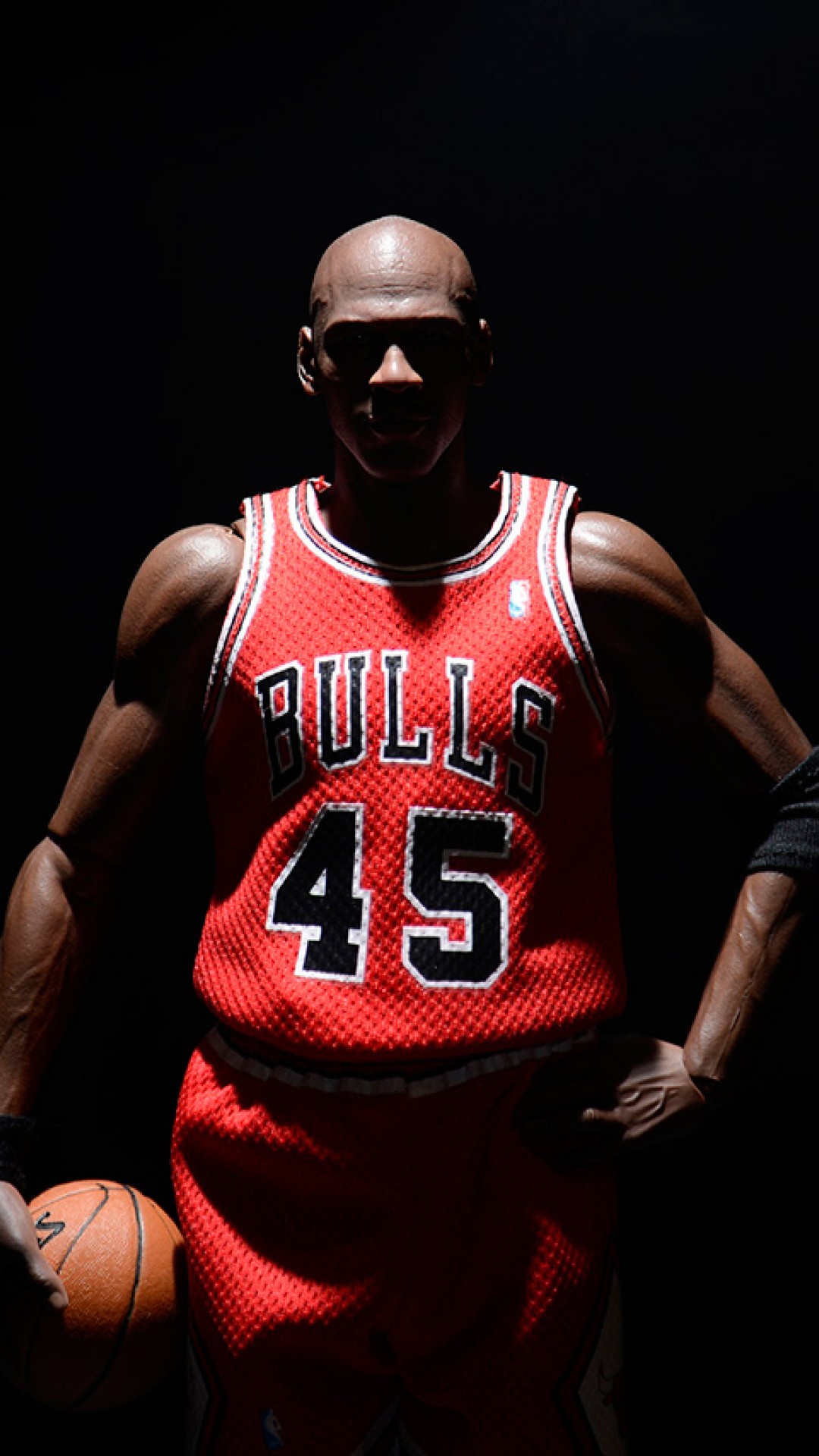 Michael Jordan in a Chicago Bulls jersey with the number 45, holding a basketball in a dimly lit setting