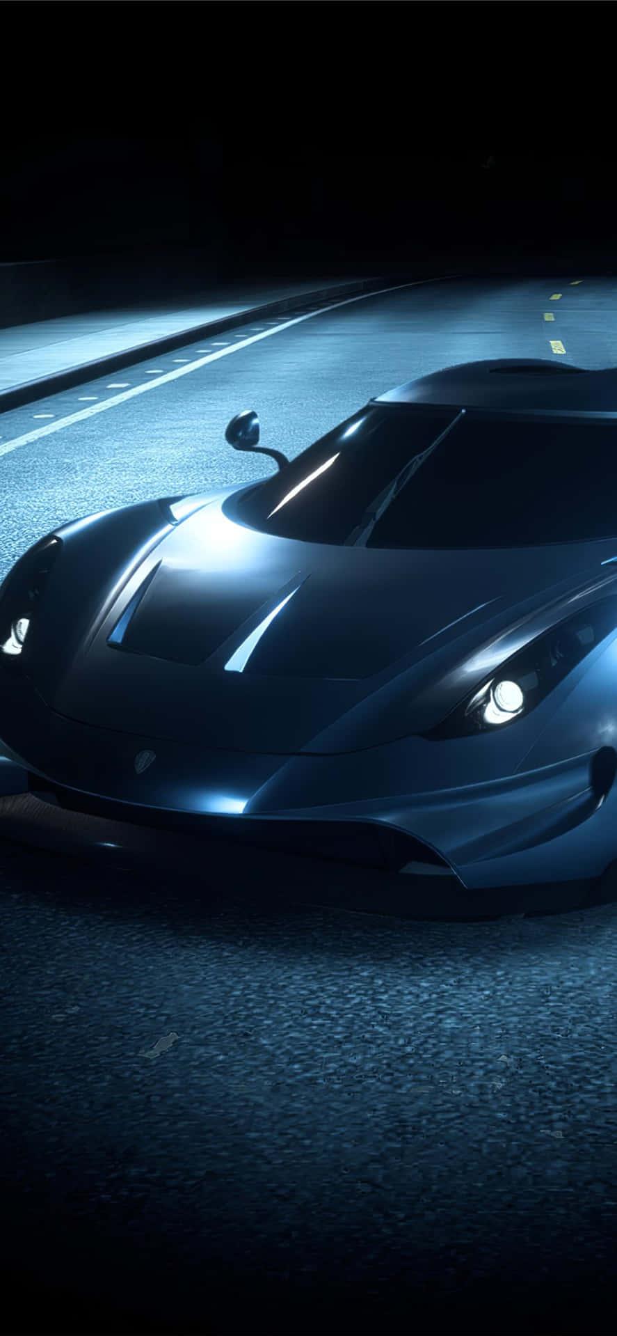 A Blue Sports Car Driving Down The Road At Night