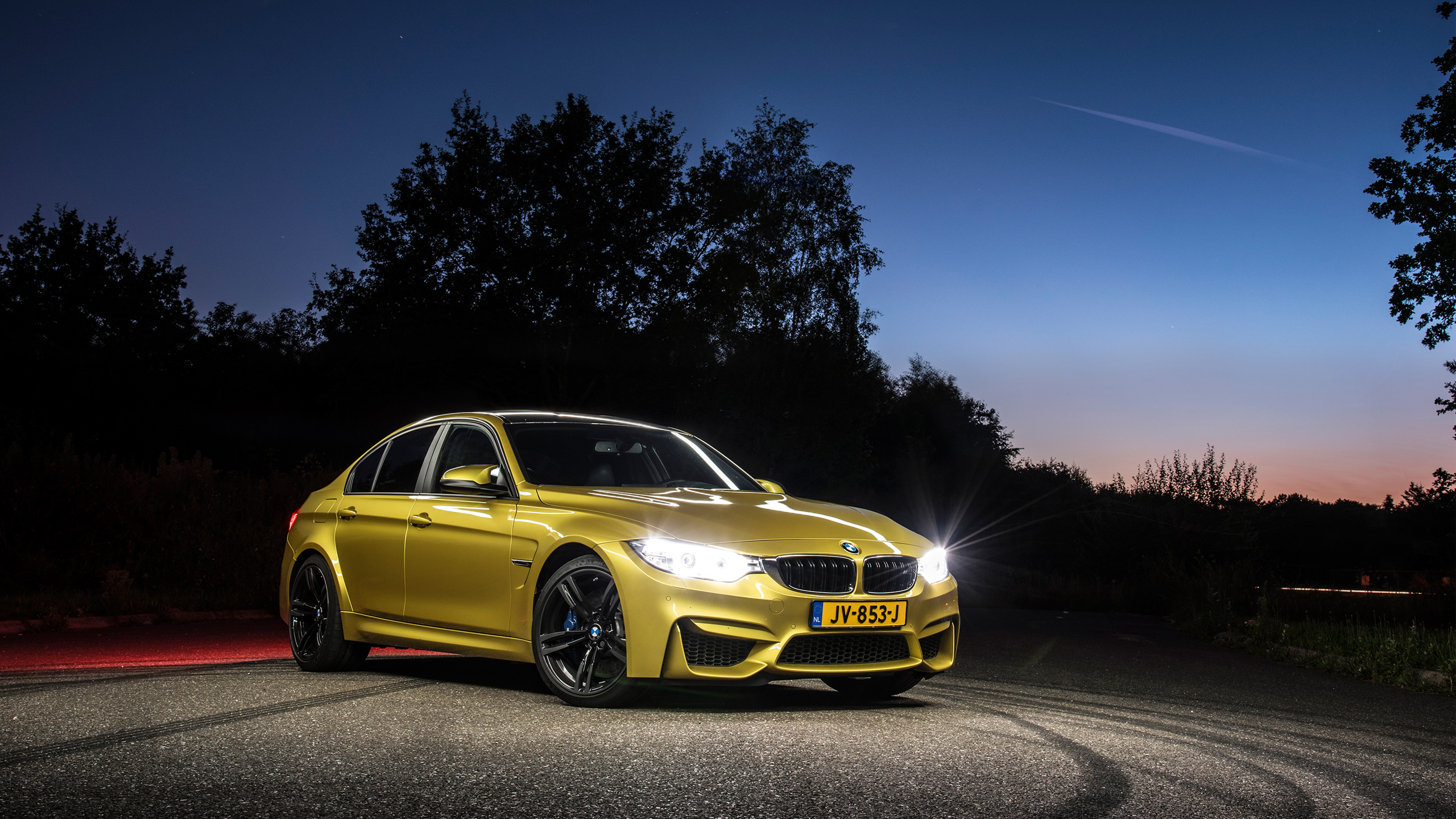 Gold BMW M3 Sedan parked on a road at dusk