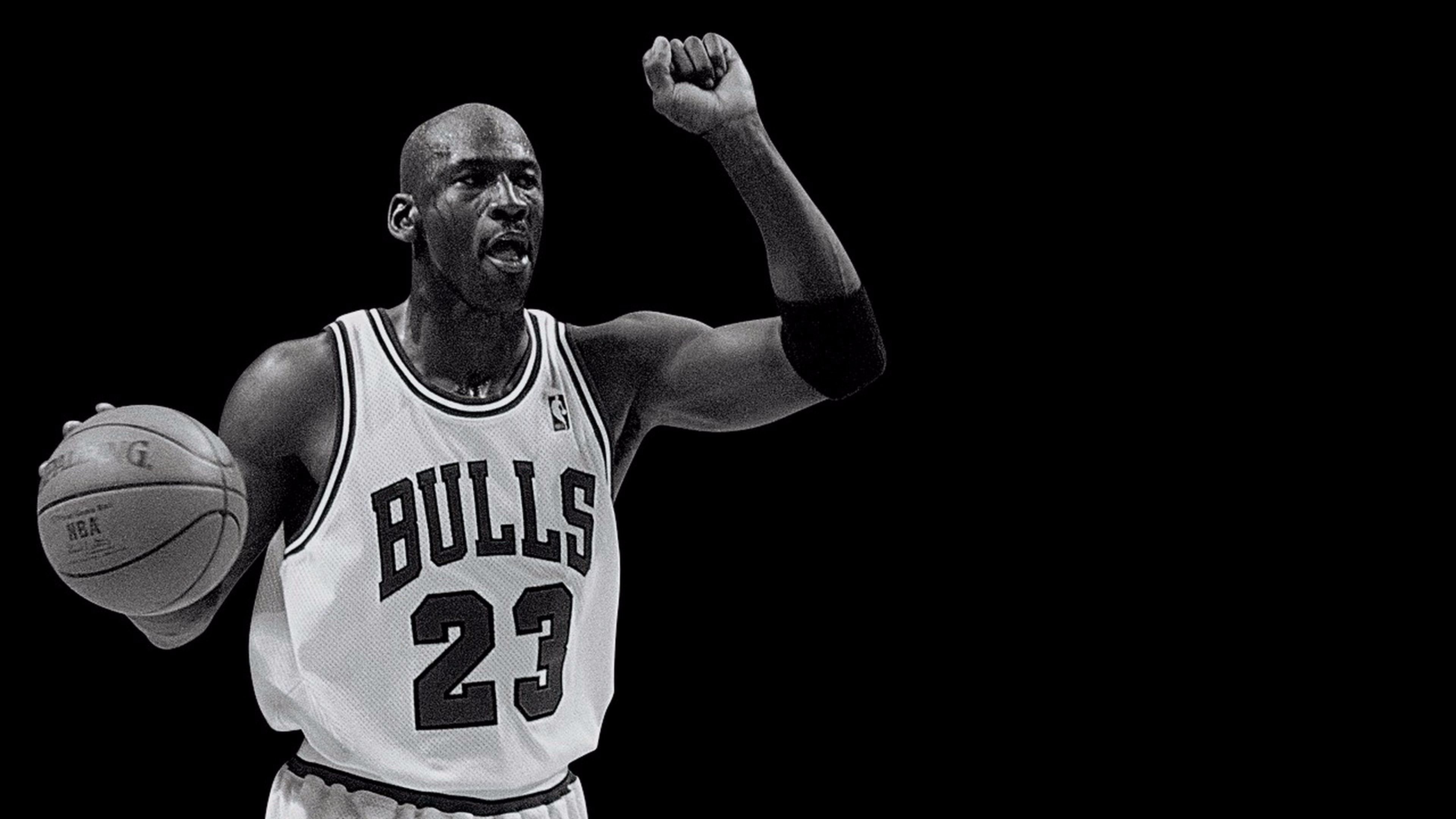 Michael Jordan raises his fist in celebration while holding a basketball during a Chicago Bulls game