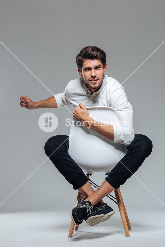 Upset Worried Man Sitting On The Chair Isolated A Gray