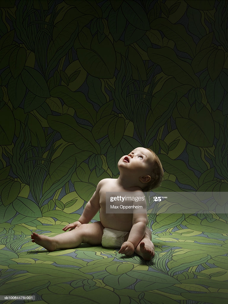 Baby Boy Sitting On Wallpaper Looking Up High Res Stock Photo