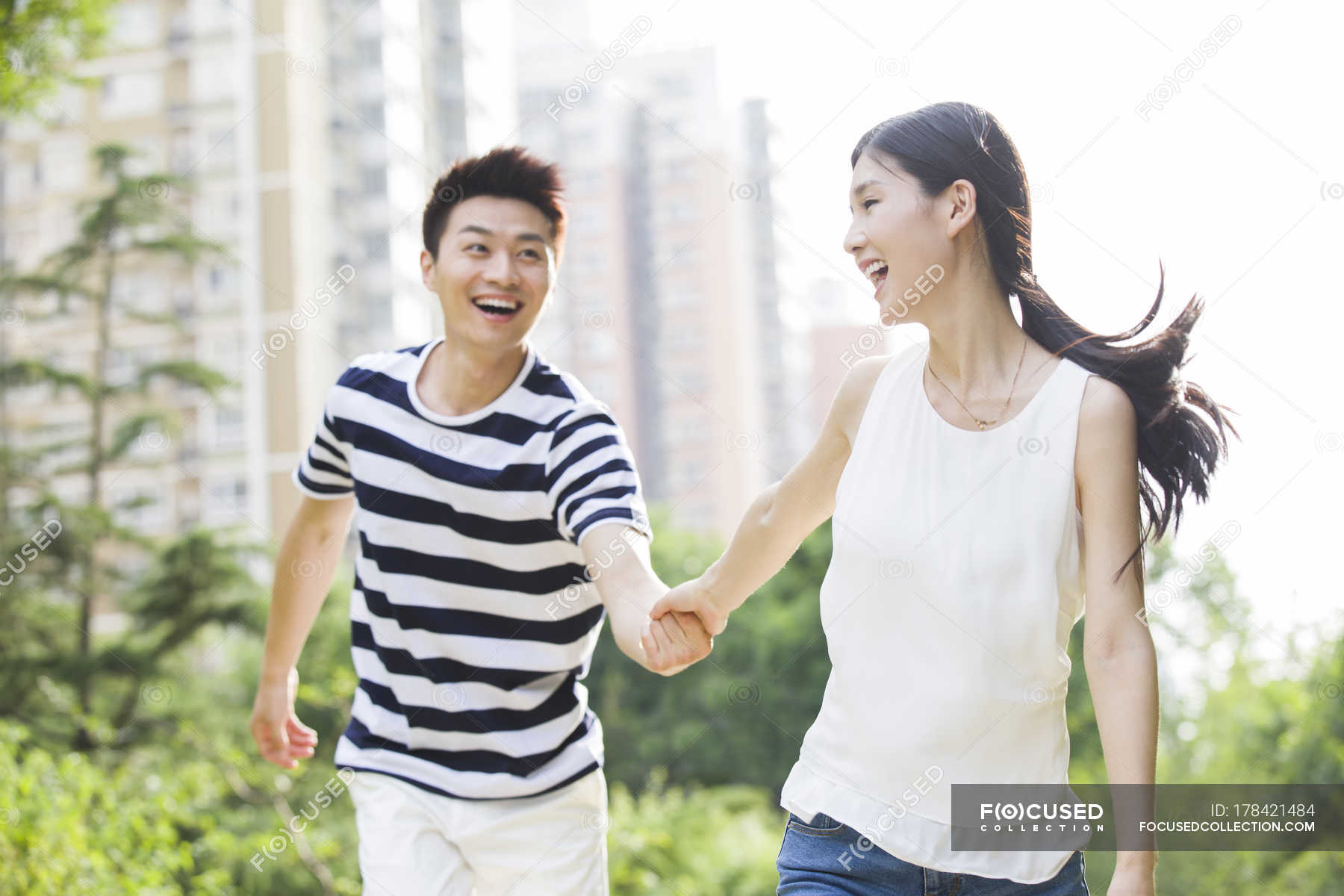 Young Chinese couple holding hands while walking in park