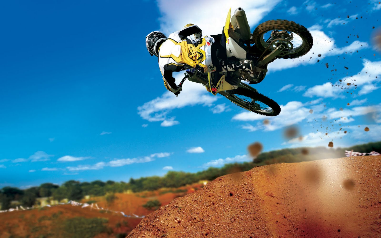 Motocross rider soaring through the air over a dirt jump against a vibrant blue sky