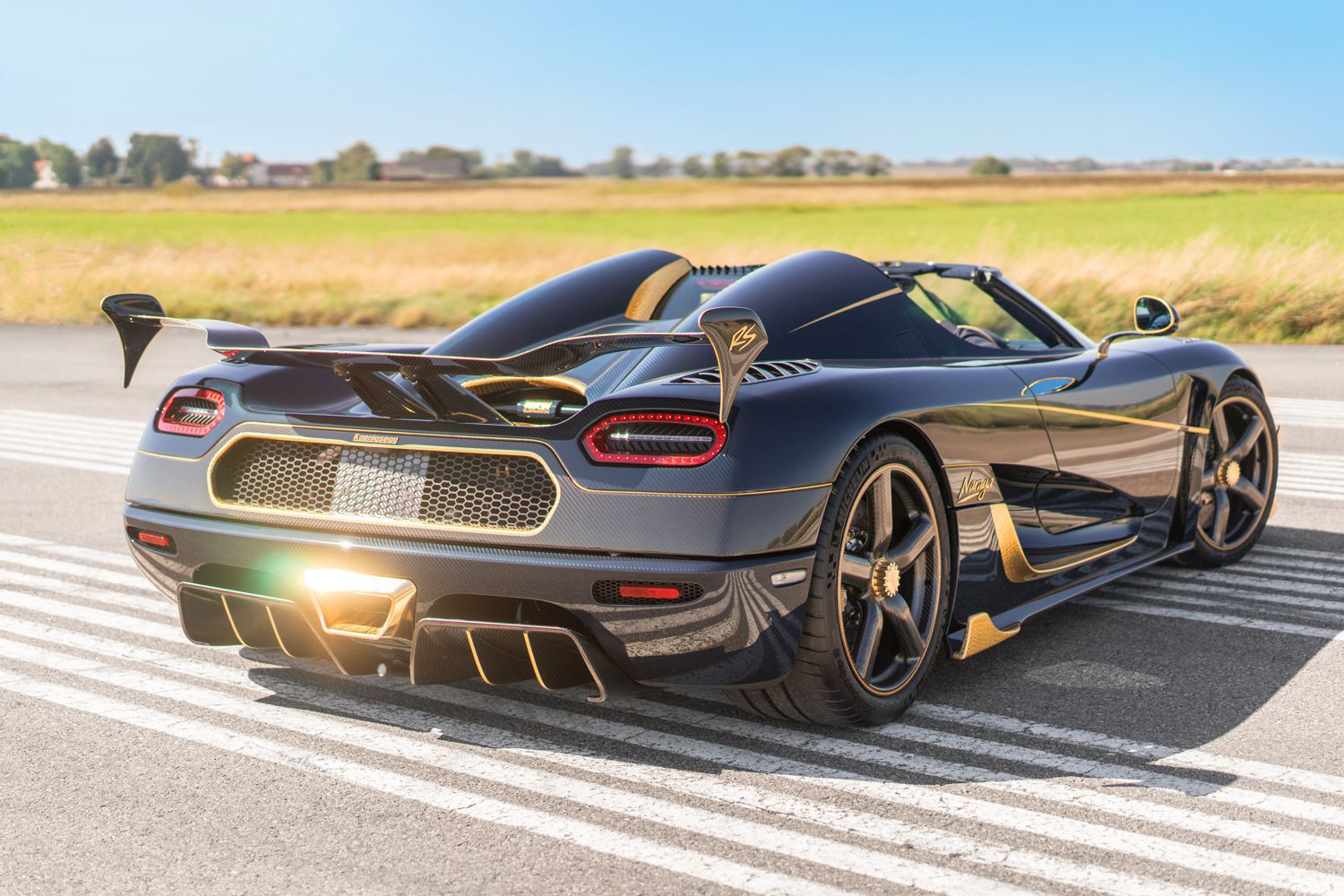 Black and Gold Koenigsegg Agera RS parked on an airstrip with gold accents and carbon fiber details
