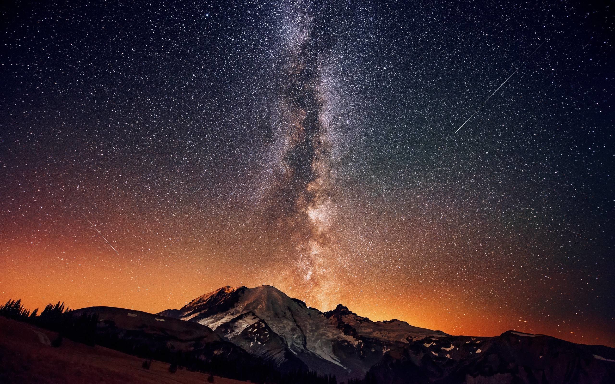 A breathtaking 4K wallpaper of the night sky, featuring the Milky Way stretching across a star-studded canvas above a majestic mountain range