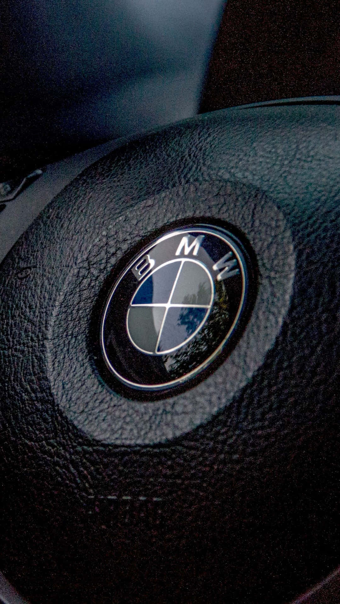 Close-up of a BMW logo on a black leather steering wheel