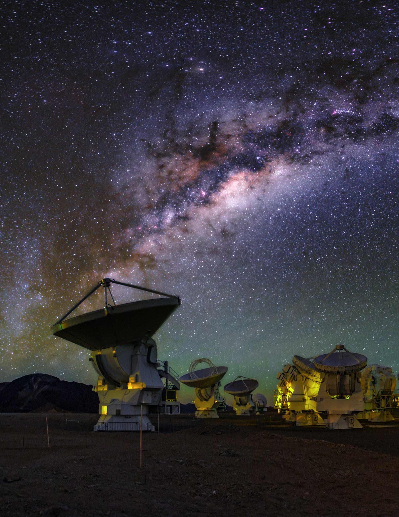 Radio telescopes silhouetted against a breathtaking backdrop of the Milky Way in the night sky