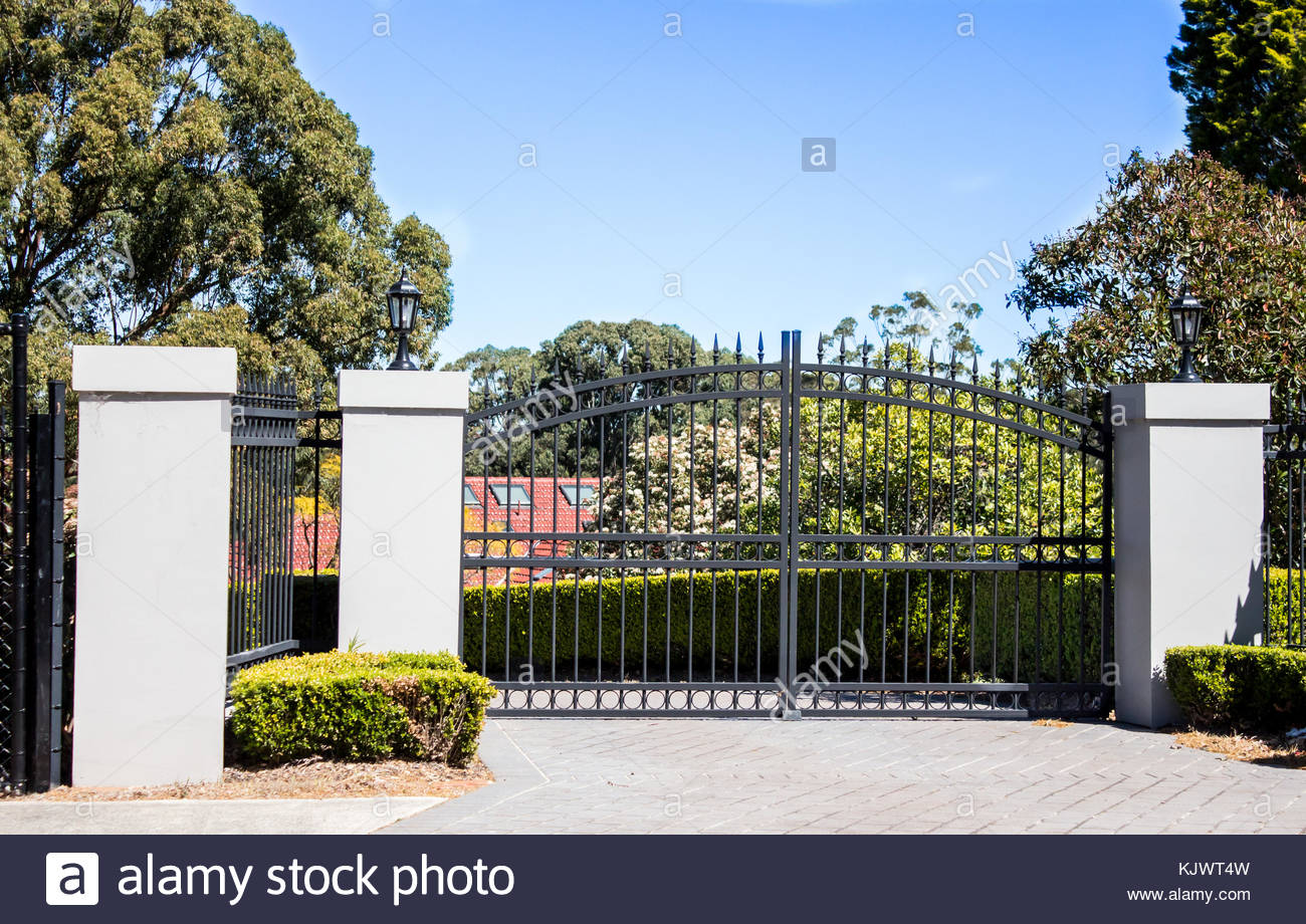 Black Metal Driveway Entrance Gates Set In Brick Fence With Garden