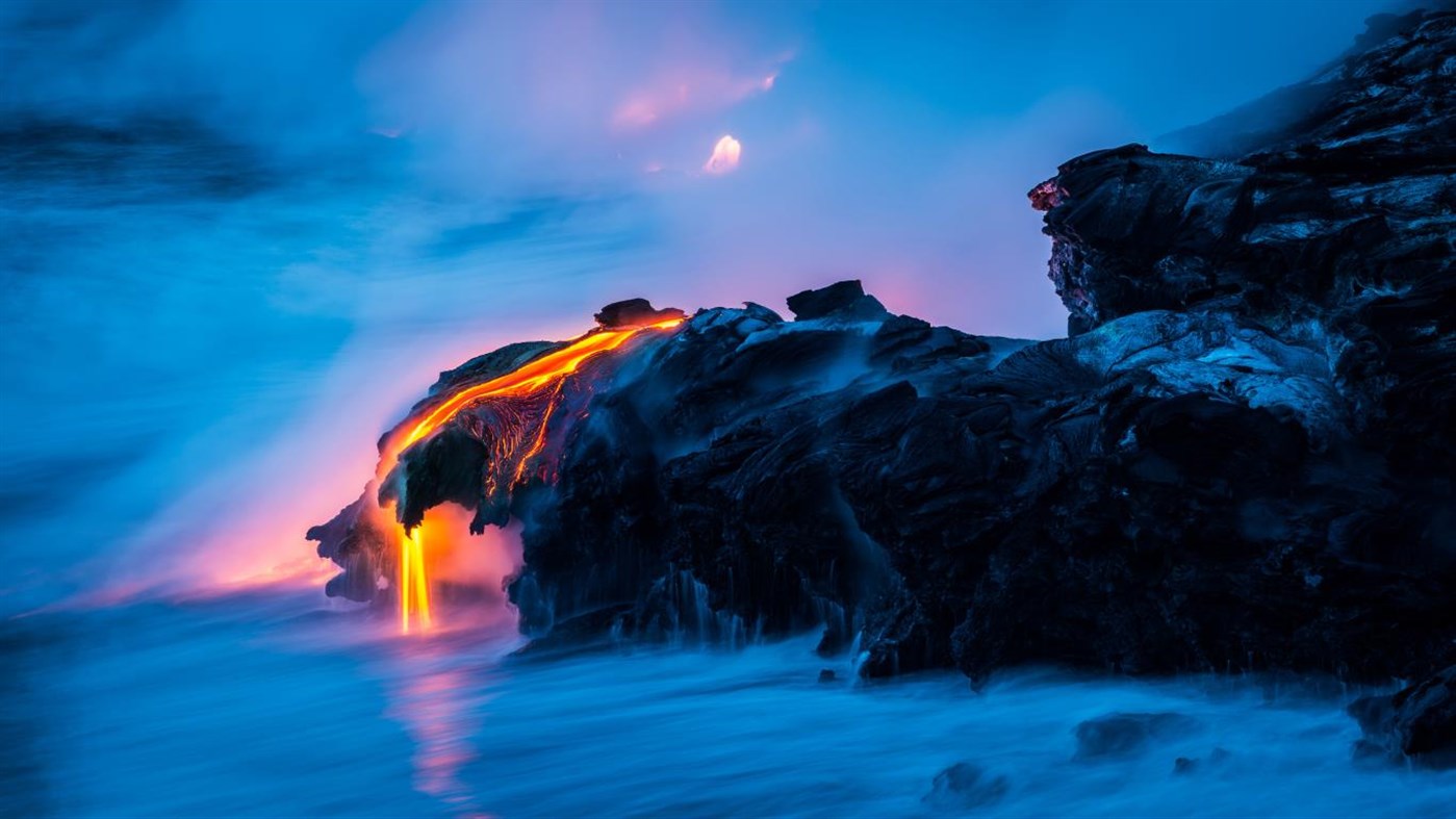 Molten lava flowing into the ocean at twilight