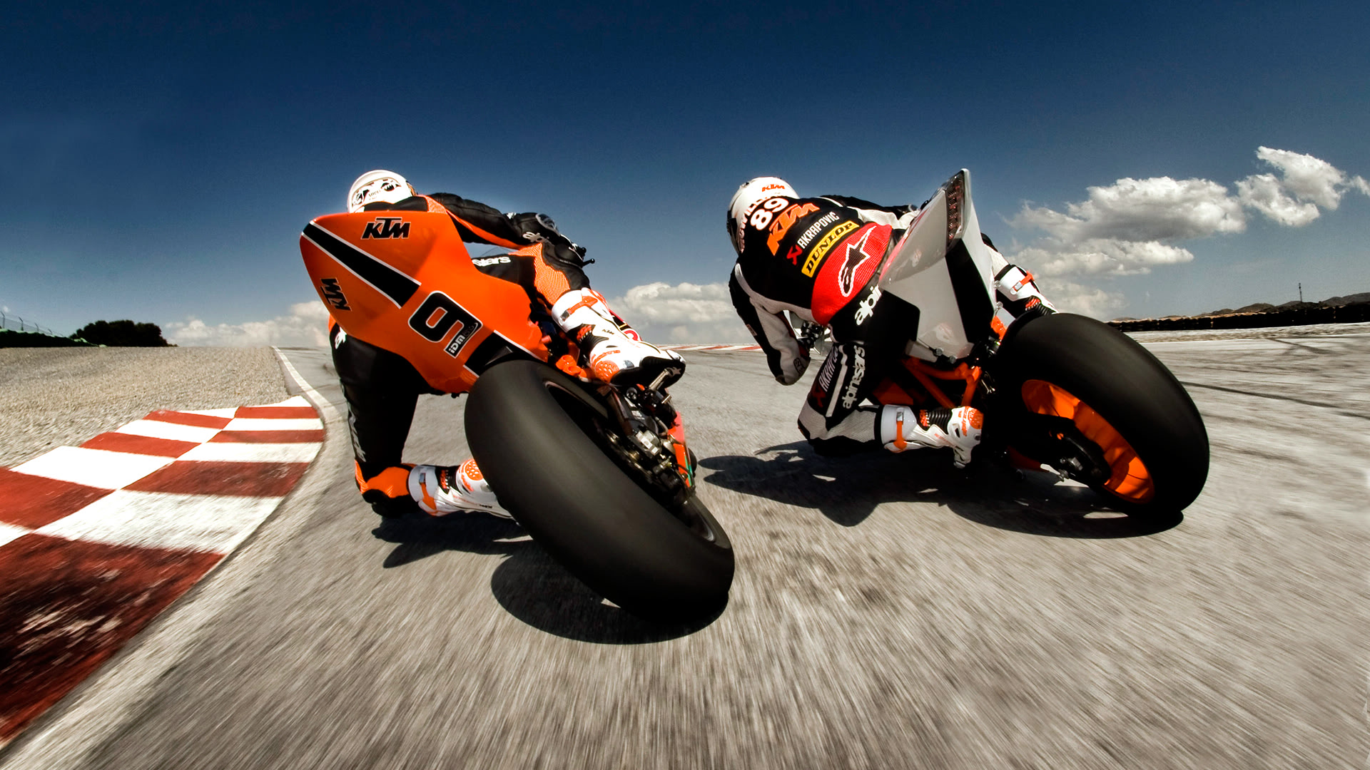 Two motorcycle racers leaning into a turn on a racetrack, showcasing speed and skill