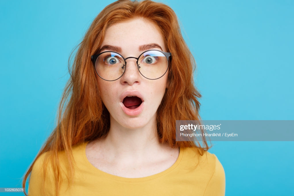 Portrait Of Shocked Woman Against Blue Background Stock Photo